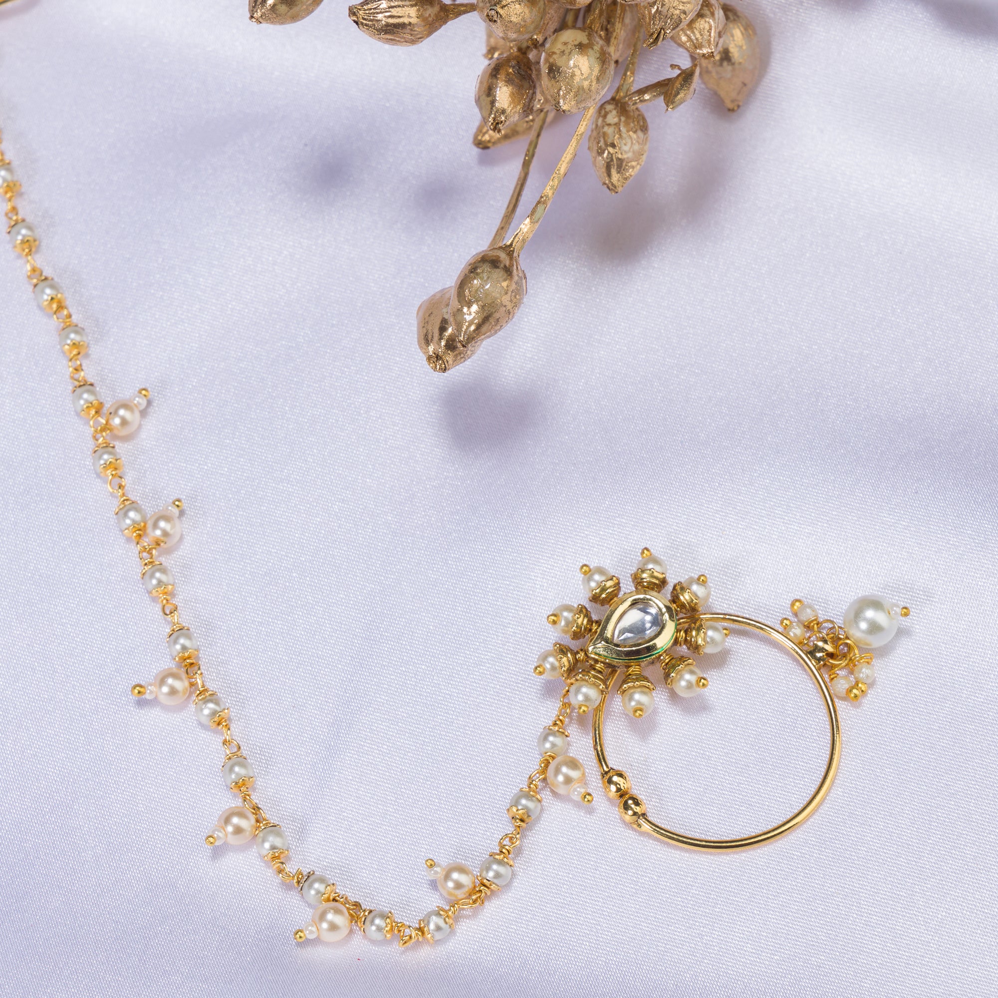 "Elegant gold-tone nose pin with pearls, perfect for festival wear, blending tradition and sophistication."