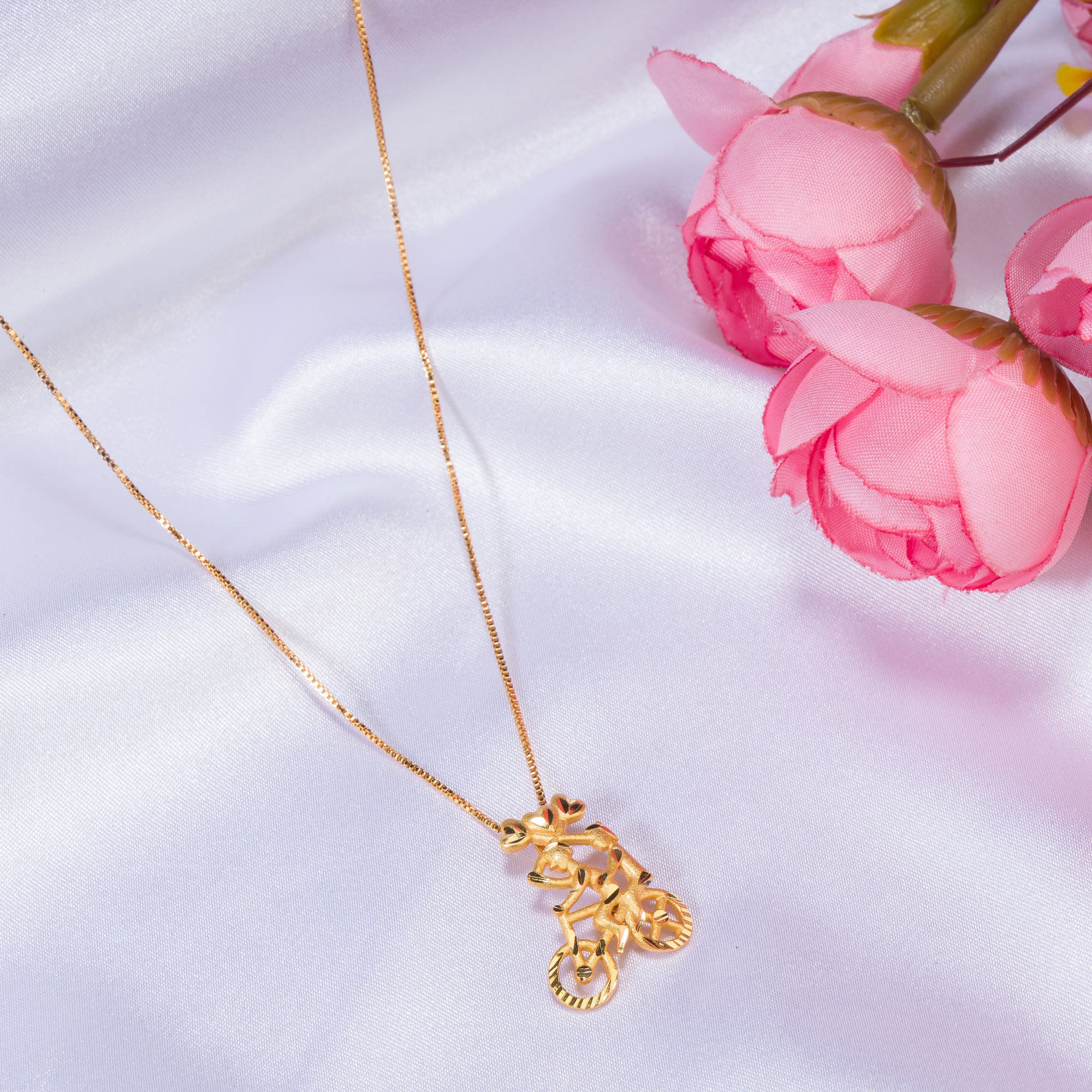 "Gold-tone pendant featuring a boy riding a bicycle, perfect for casual wear, with a fun and unique design."