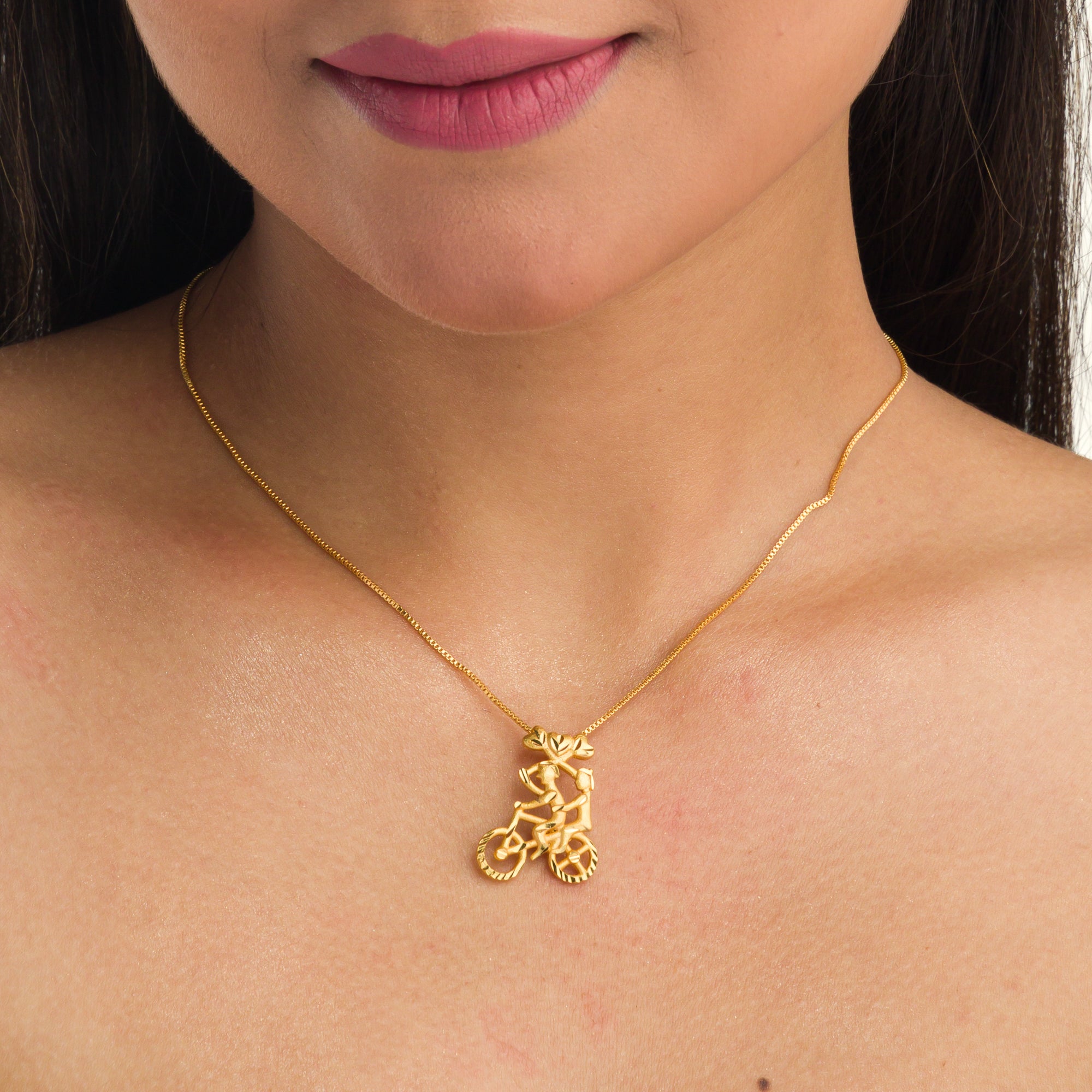 "Gold-tone pendant featuring a boy riding a bicycle, perfect for casual wear, with a fun and unique design."