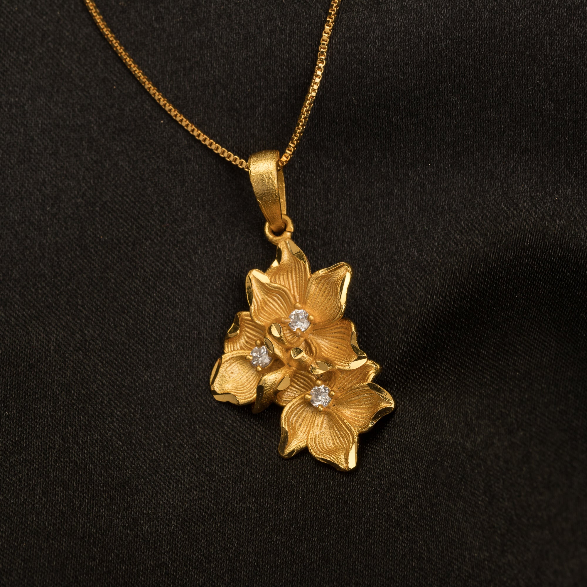 "Gold-tone pendant featuring three flowers, perfect for casual wear, offering a charming, delicate look."