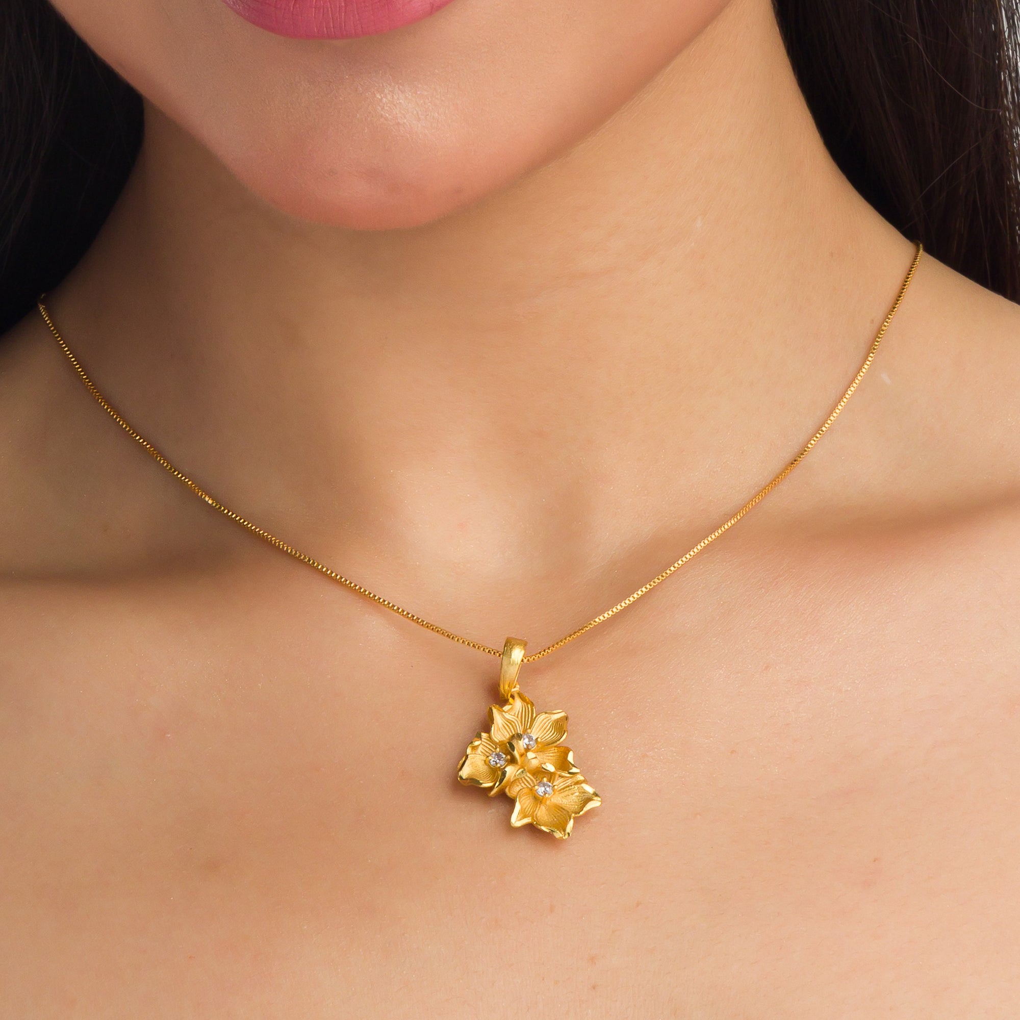 "Gold-tone pendant featuring three flowers, perfect for casual wear, offering a charming, delicate look."