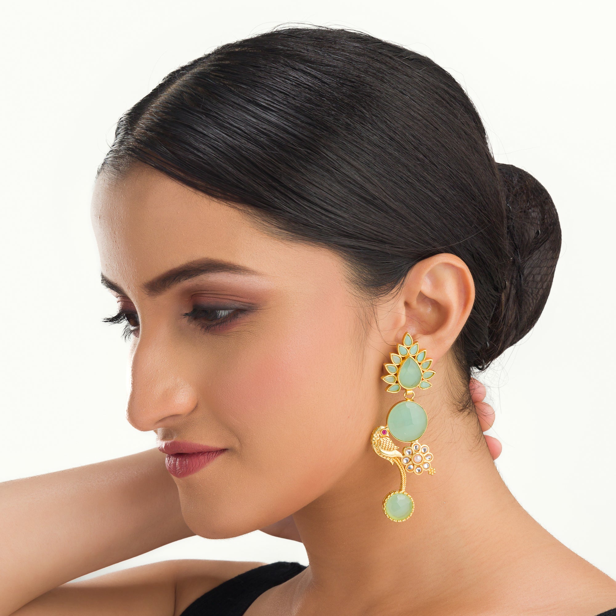 "Gold-tone dangler earrings with light green accents blend warmth and freshness for a chic, eye-catching festival look."