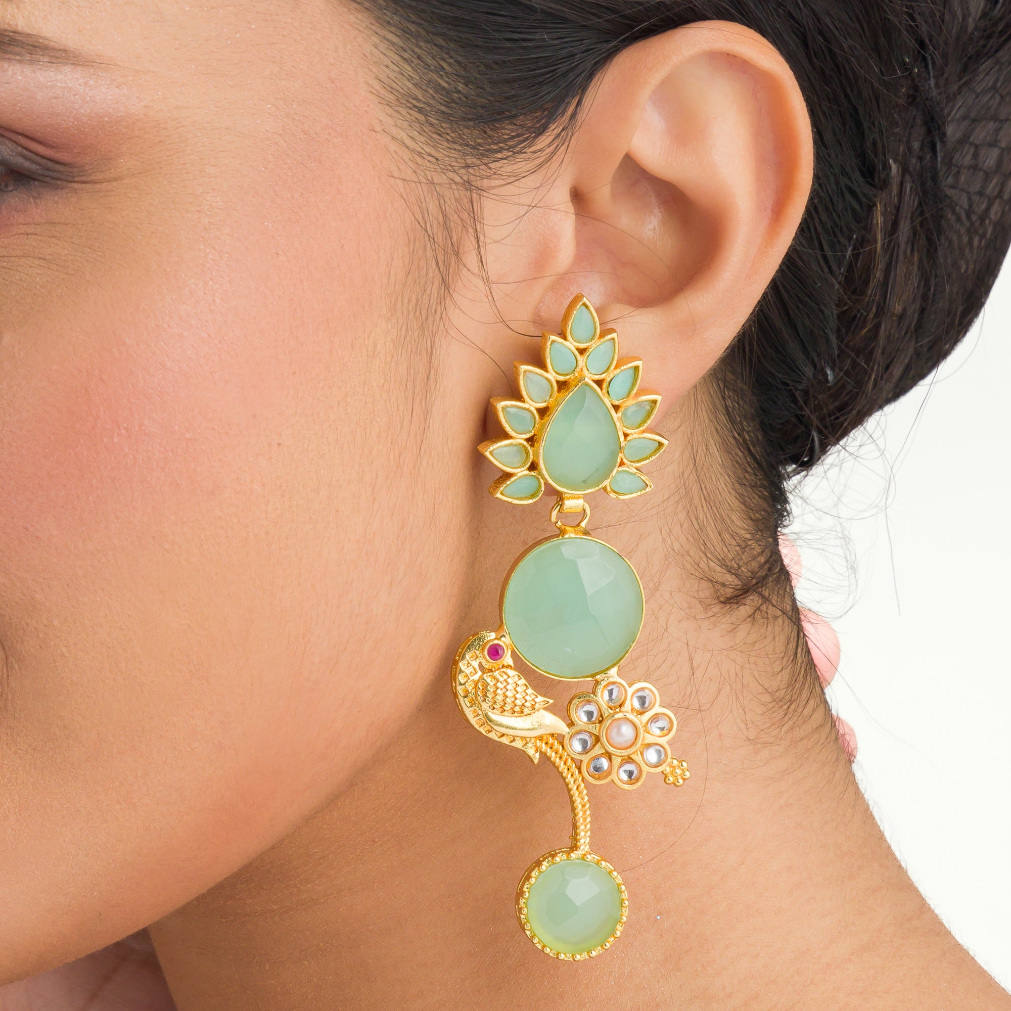 "Gold-tone dangler earrings with light green accents blend warmth and freshness for a chic, eye-catching festival look."