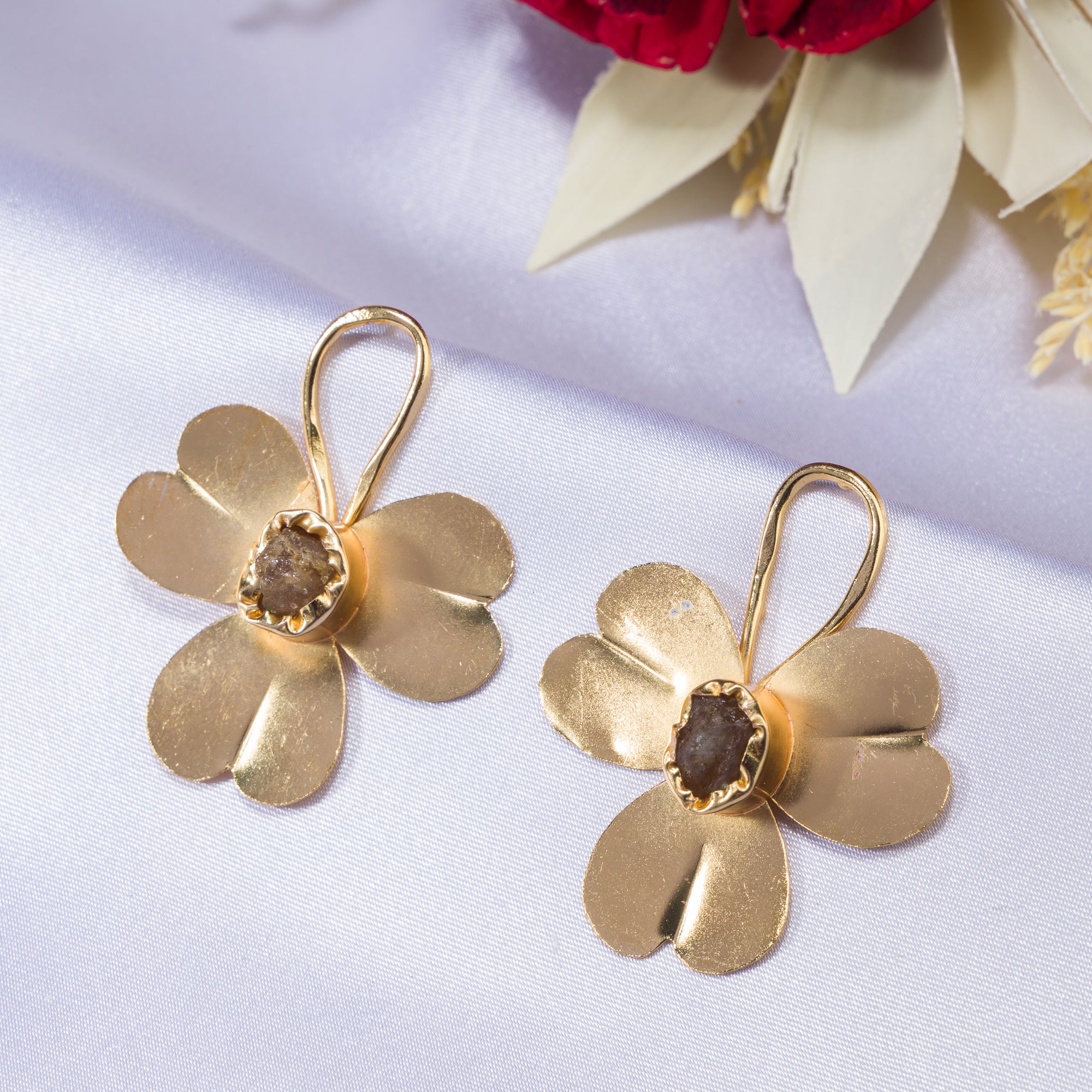 "Gold-tone flower studs with uncut stones offer timeless elegance for any occasion."