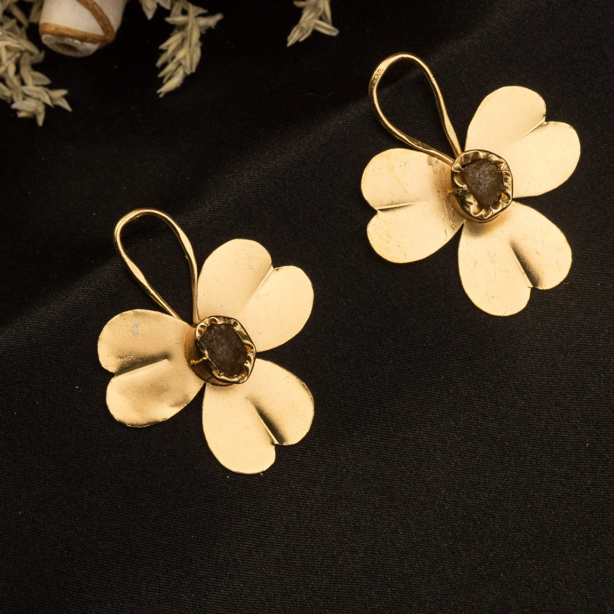 "Gold-tone flower studs with uncut stones offer timeless elegance for any occasion."