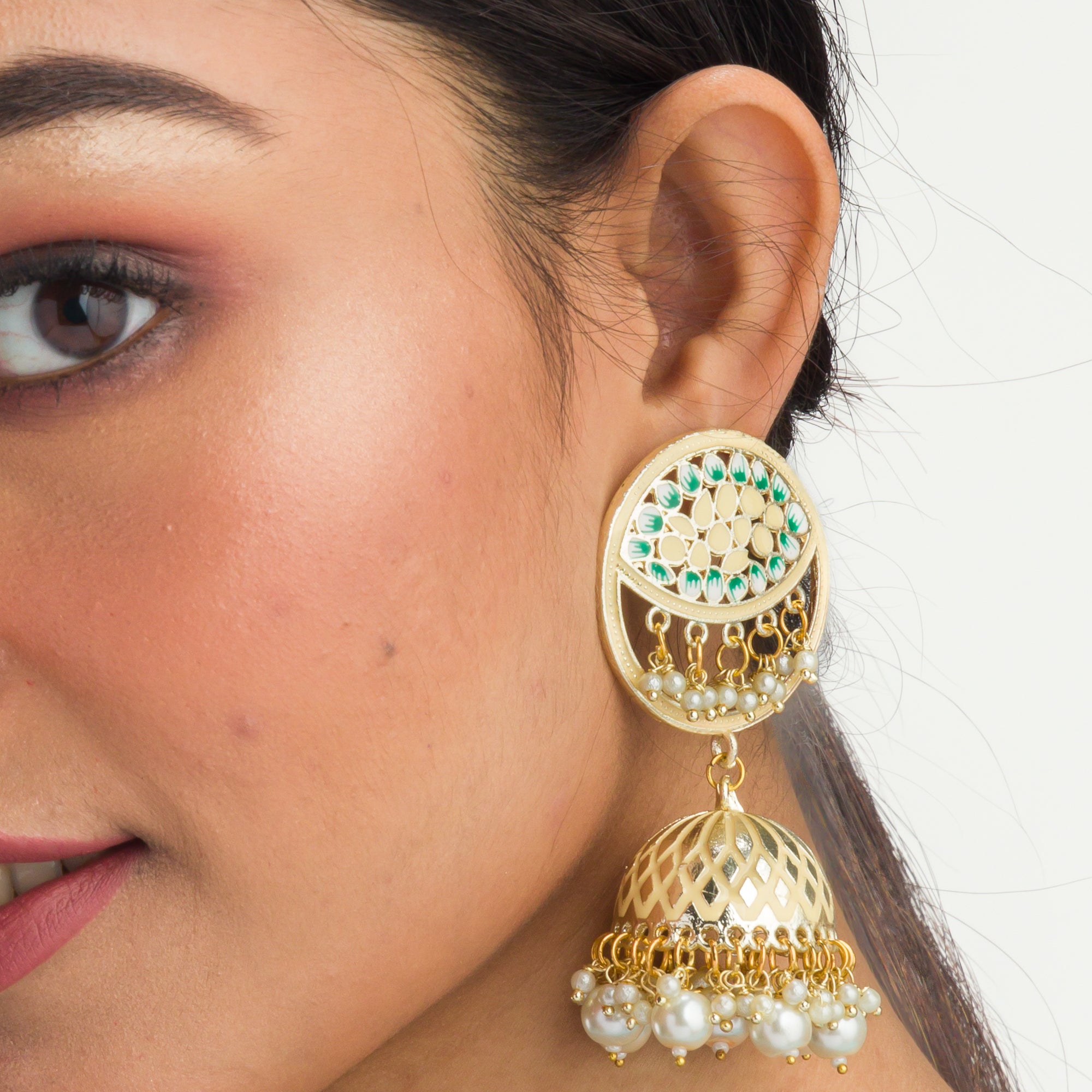 "Gold-tone jhumka with a green accent adds a vibrant twist to traditional style."