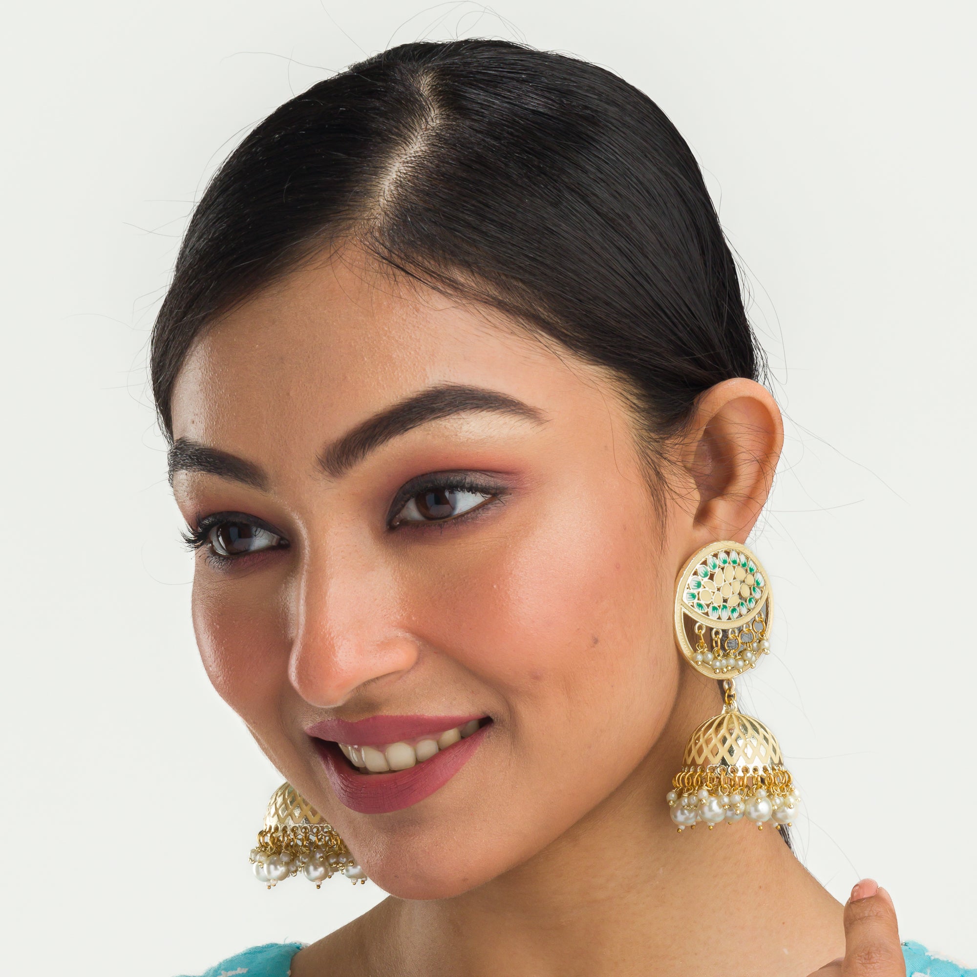 "Gold-tone jhumka with a green accent adds a vibrant twist to traditional style."