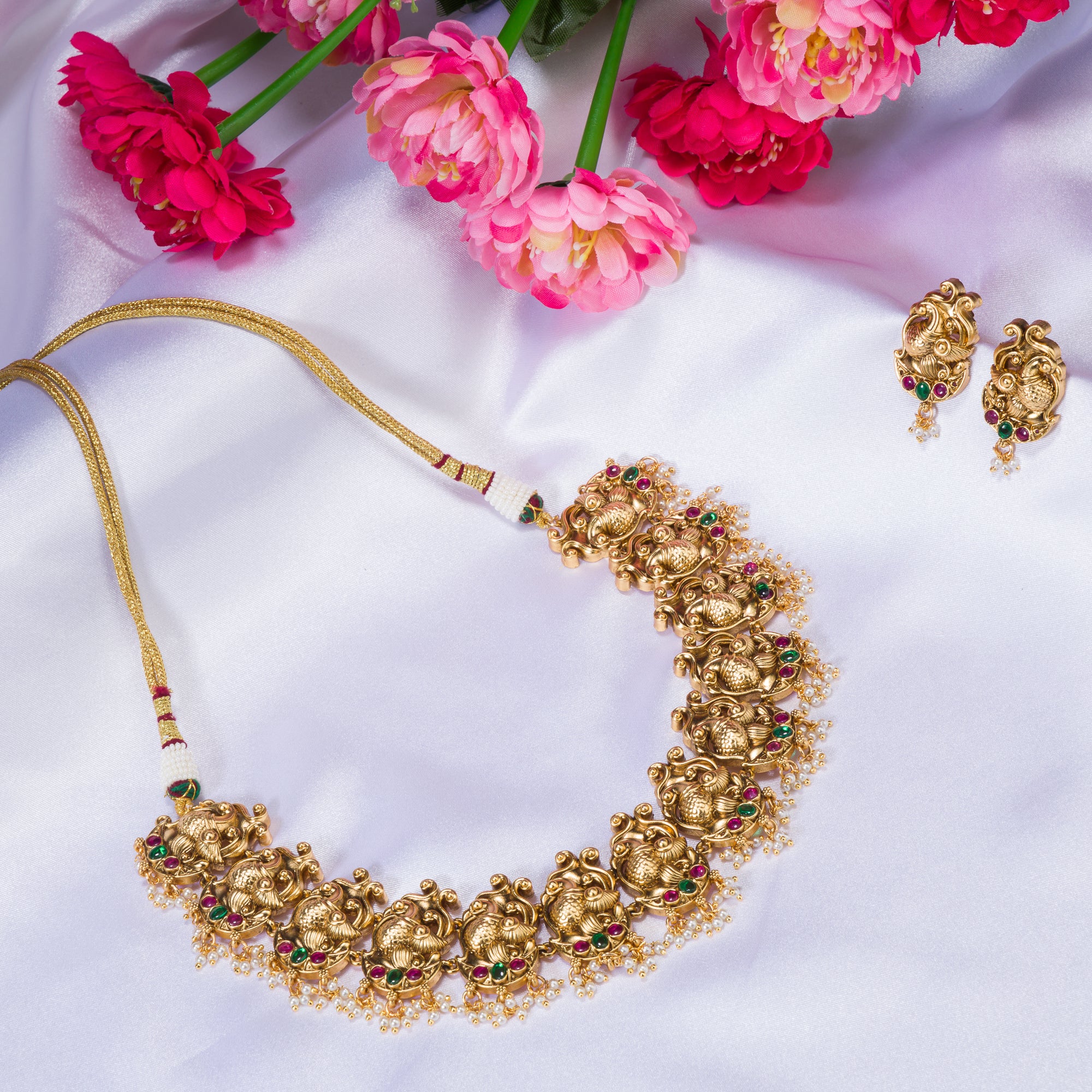 Vibrant gold-tone necklace with red, green stones, and white pearls for a stunning party look.
