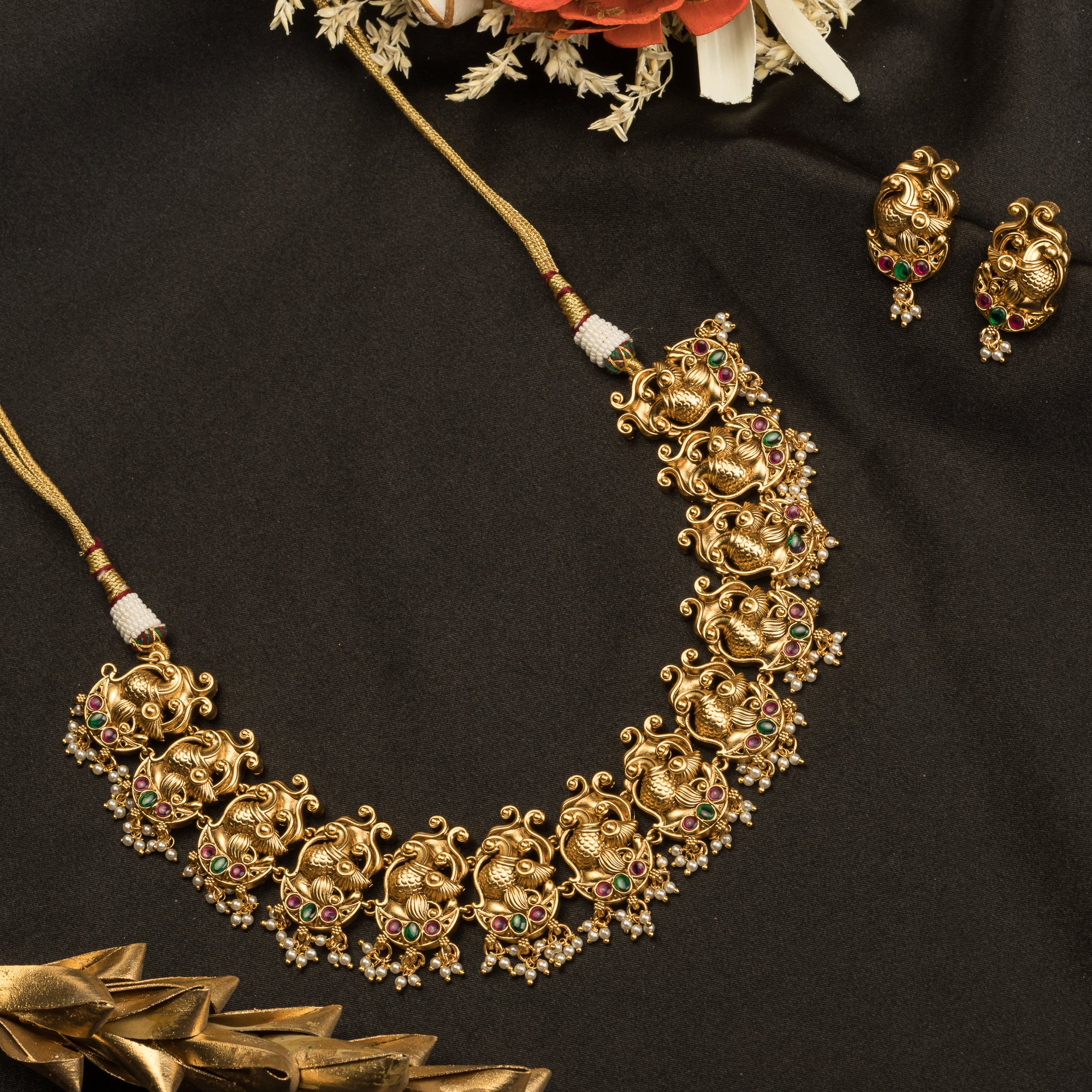 Vibrant gold-tone necklace with red, green stones, and white pearls for a stunning party look.