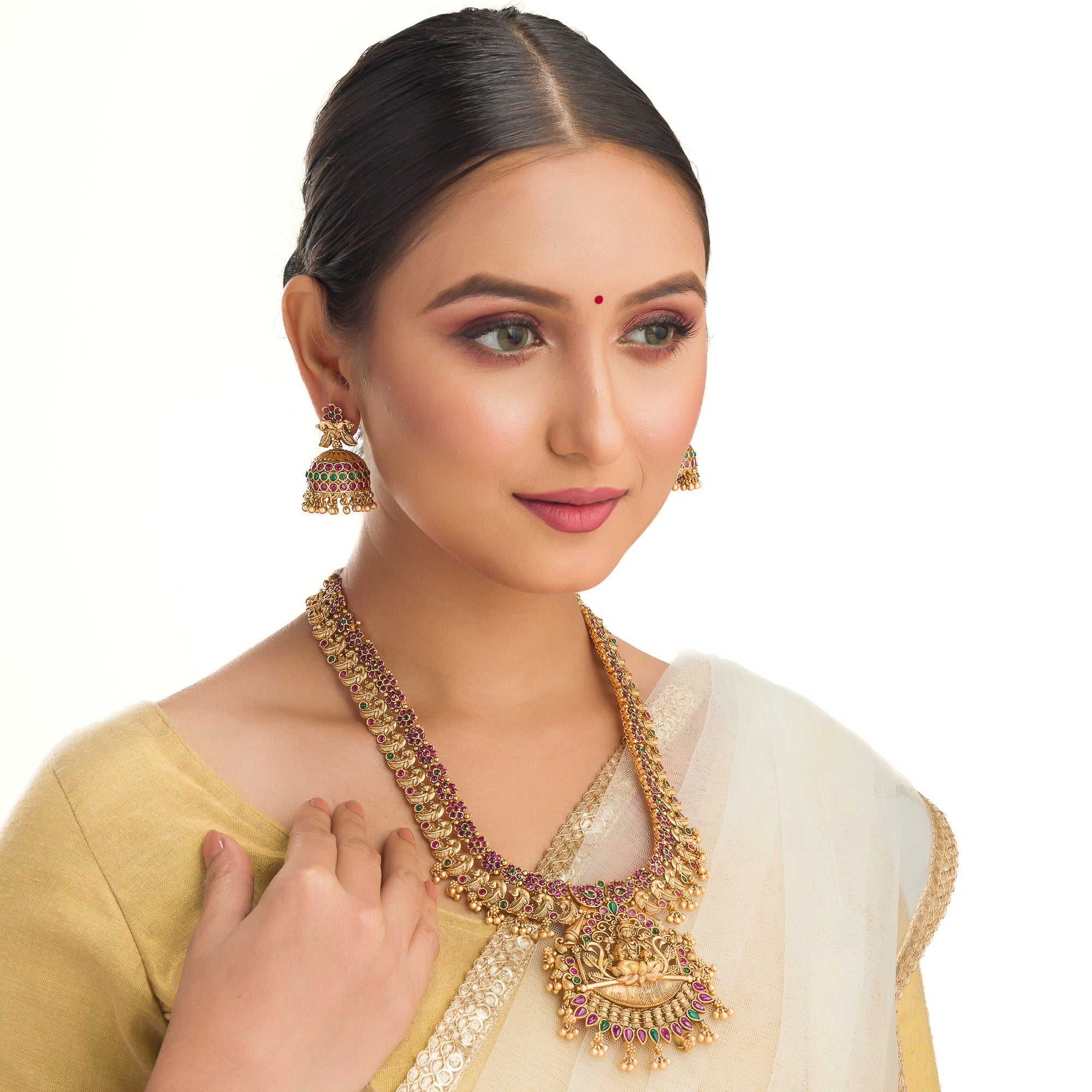 Traditional temple jewelry with red and green stones radiates timeless opulence and charm.