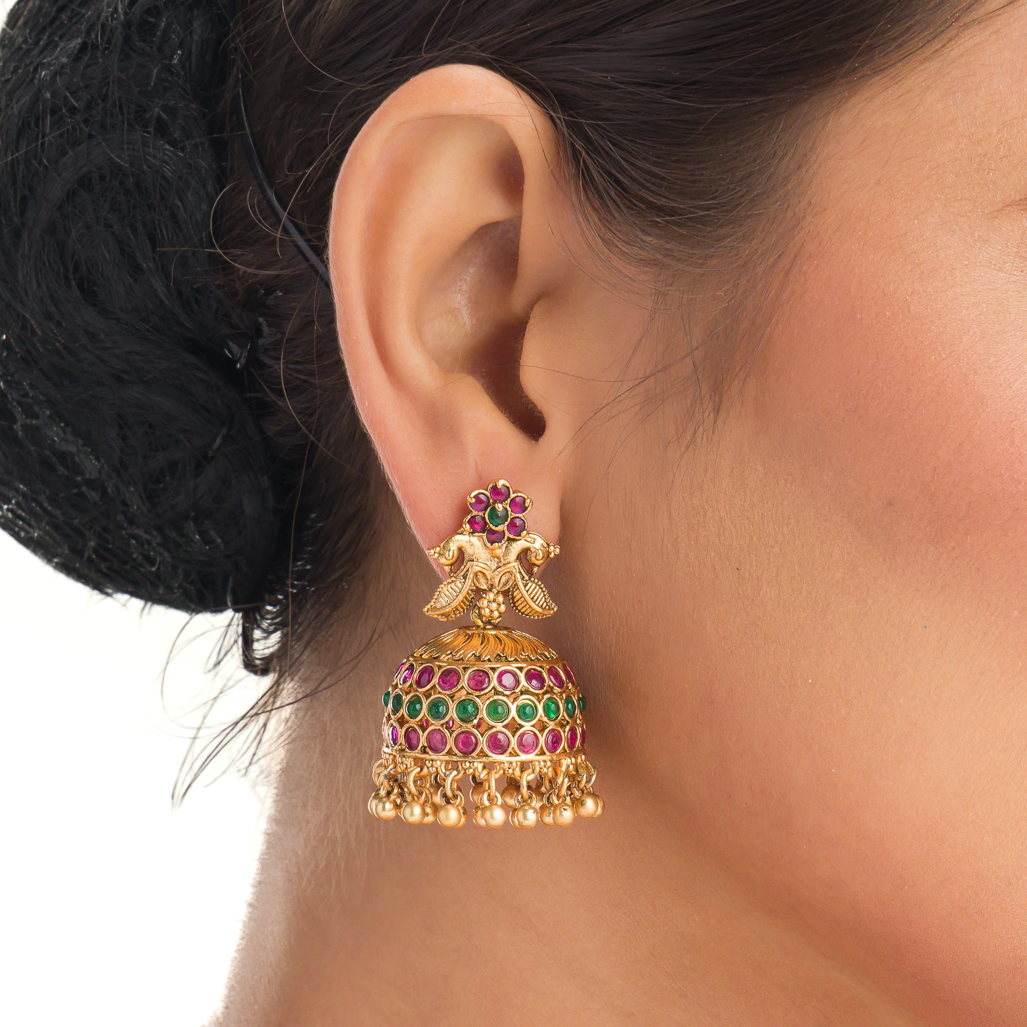 Traditional temple jewelry with red and green stones radiates timeless opulence and charm.