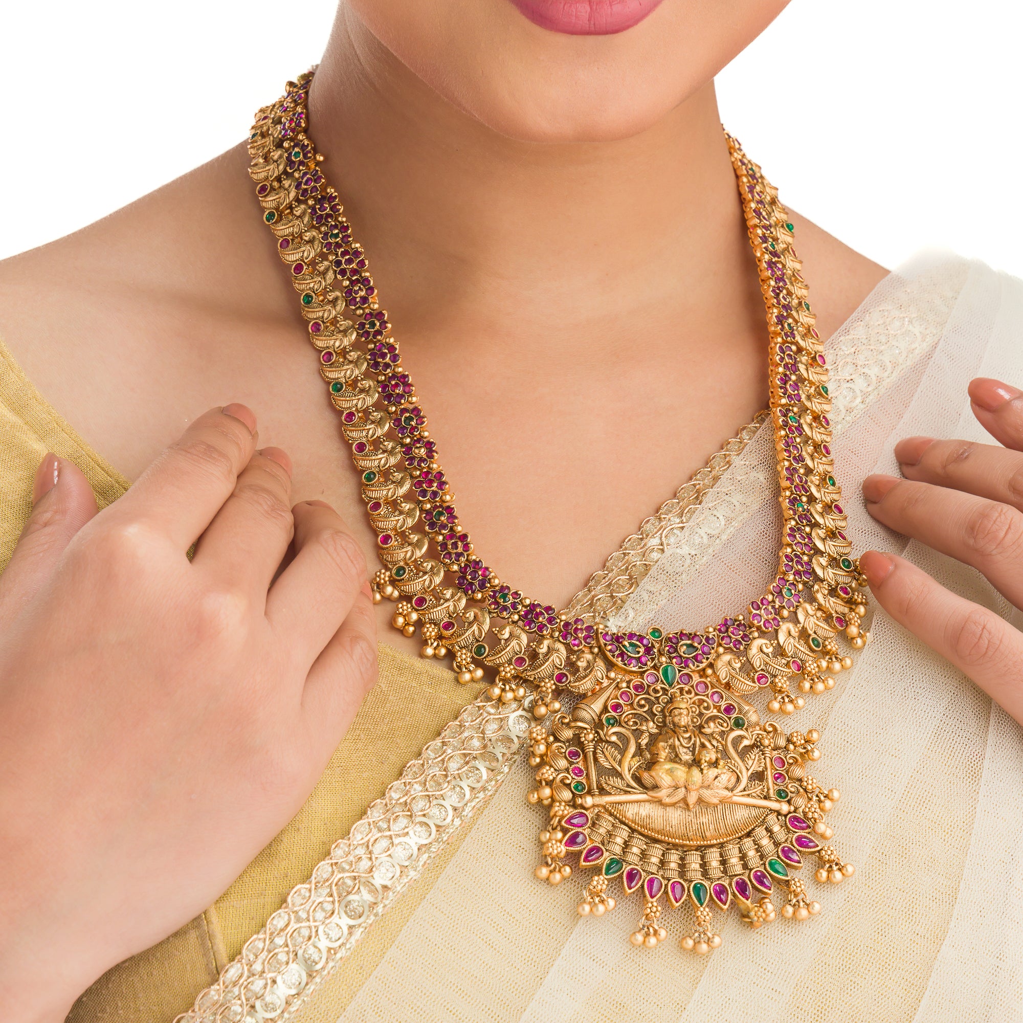 Traditional temple jewelry with red and green stones radiates timeless opulence and charm.
