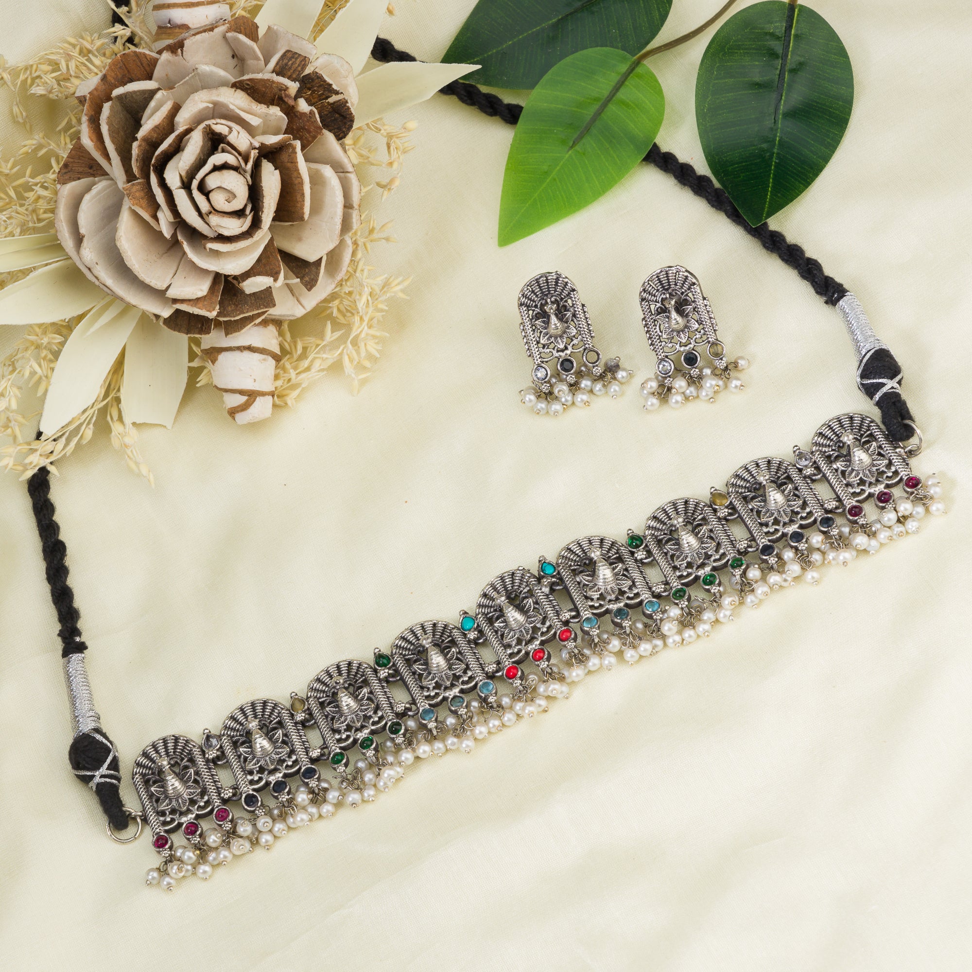 "Oxidized peacock choker with white pearls and colorful stones radiates vintage charm."