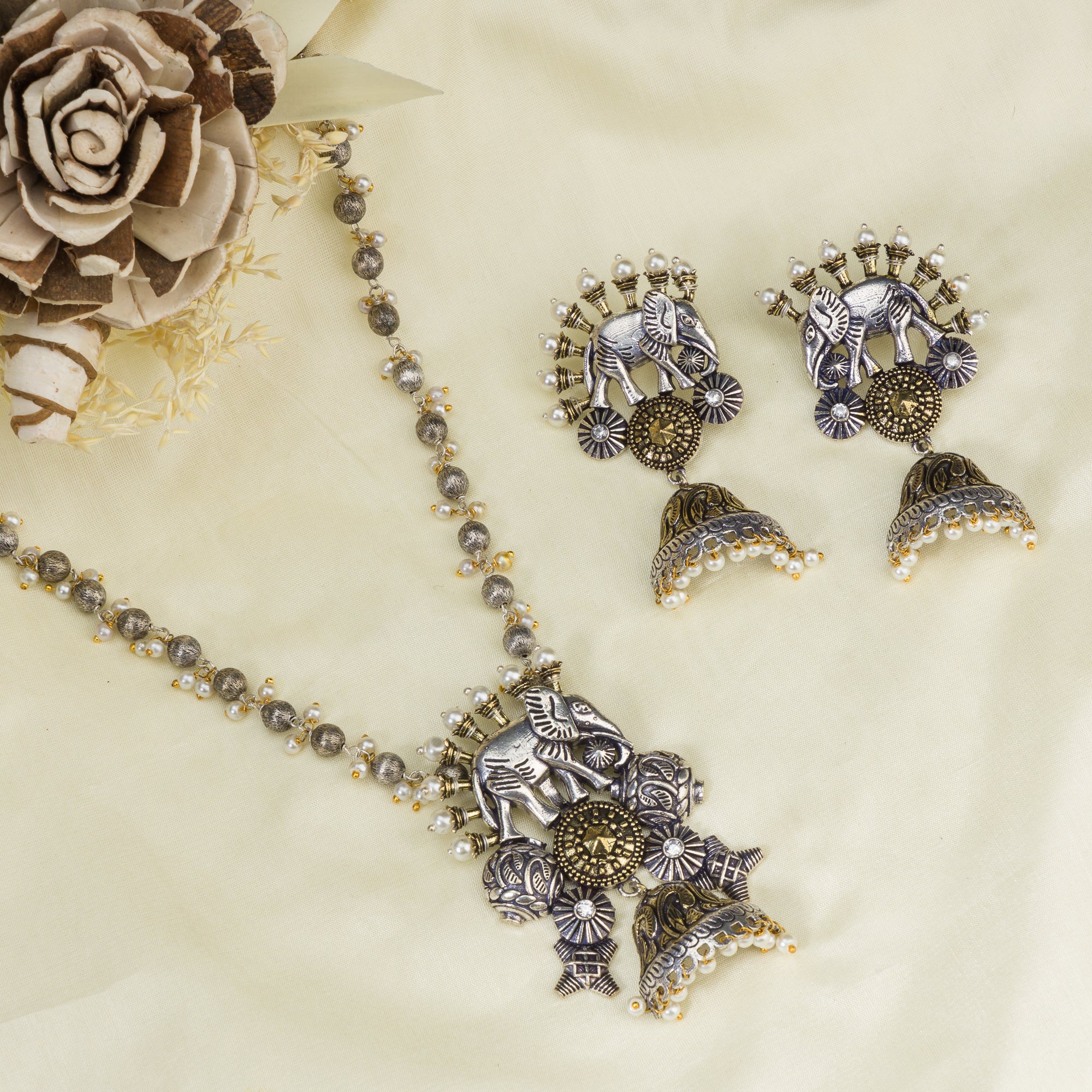 An oxidized dual-colour necklace with elephant and white pearls adds vintage charm and elegance.