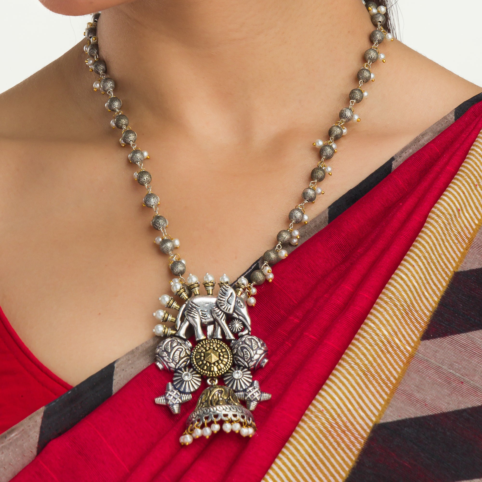An oxidized dual-colour necklace with elephant and white pearls adds vintage charm and elegance.