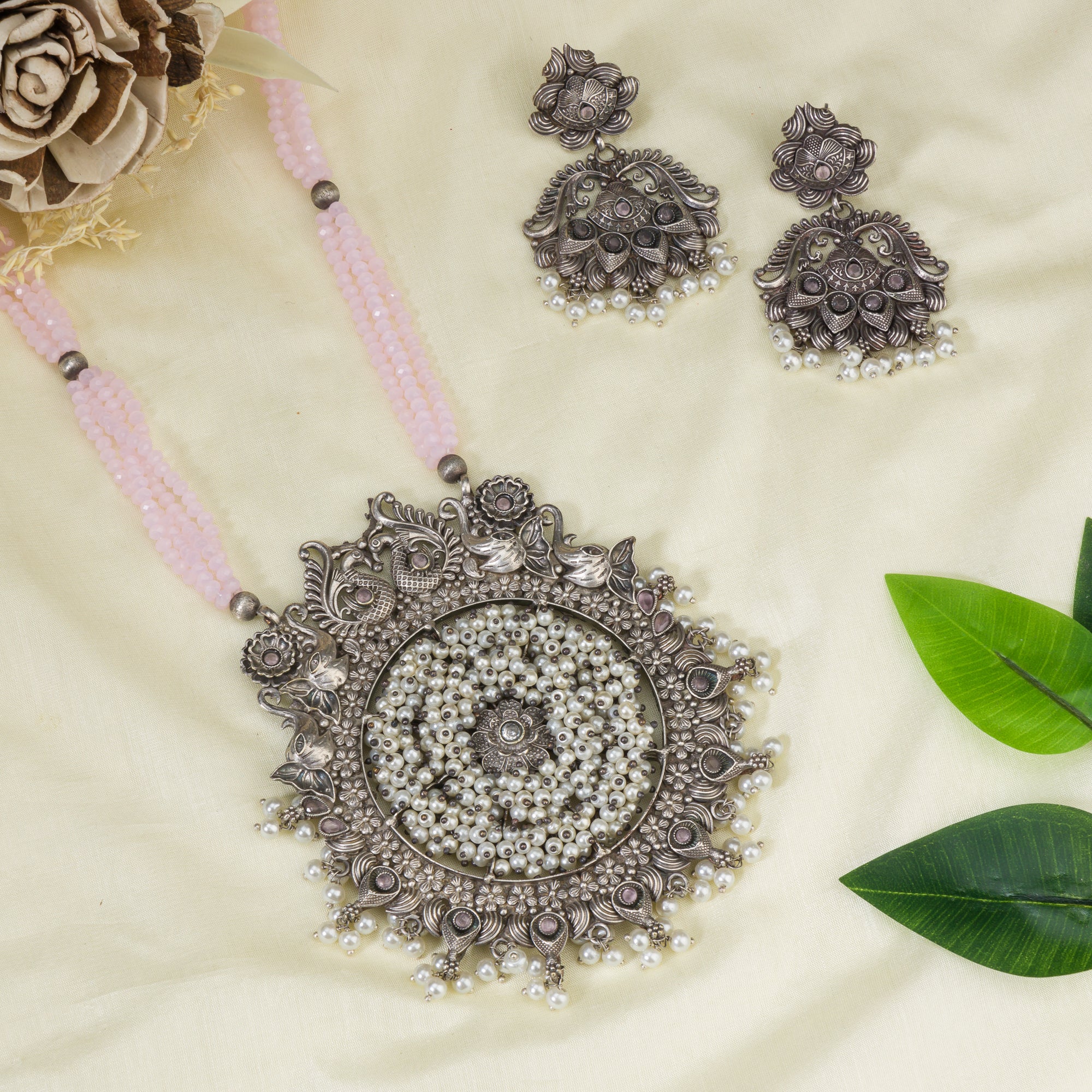 "Long oxidized necklace with pink and white pearls adds vintage elegance."