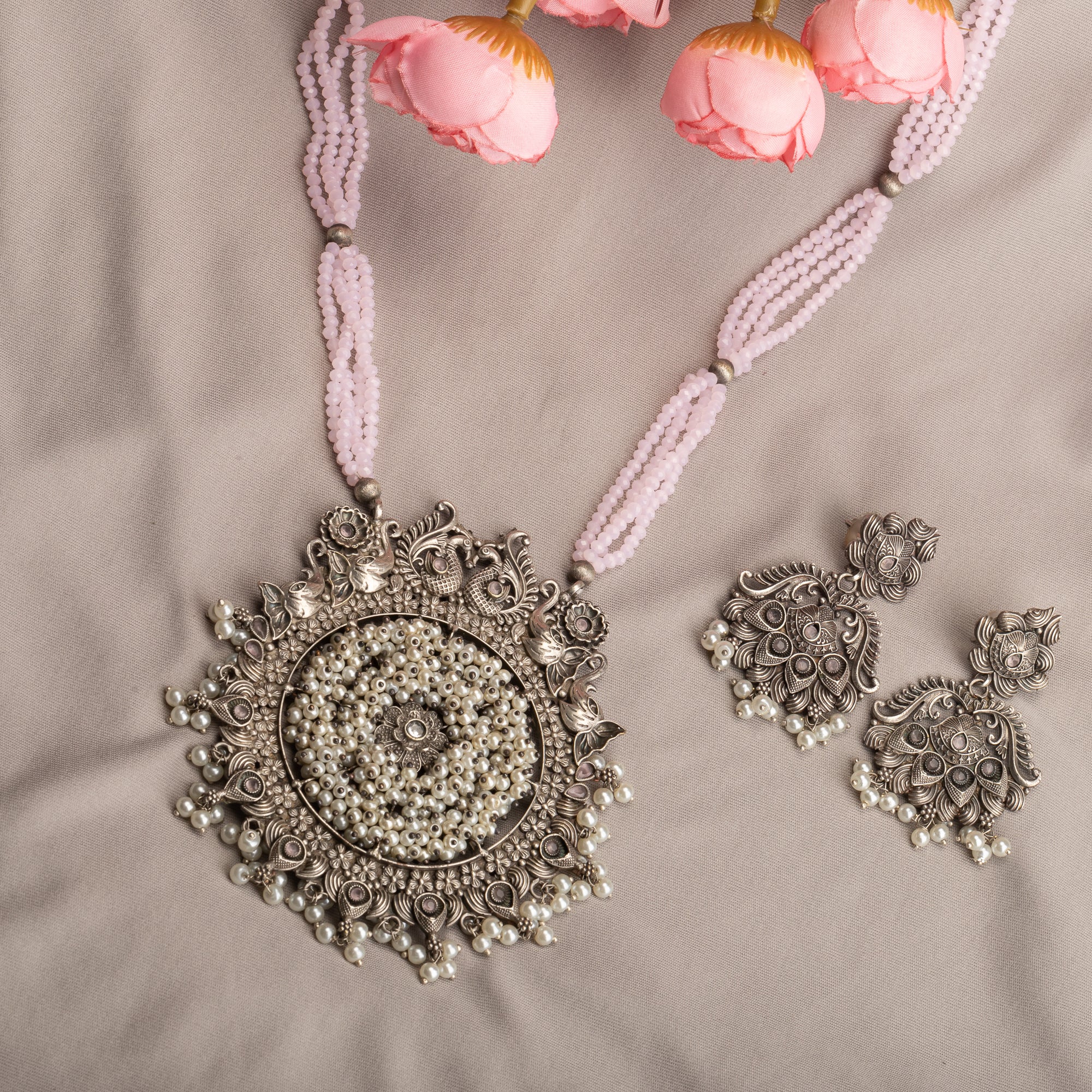 "Long oxidized necklace with pink and white pearls adds vintage elegance."