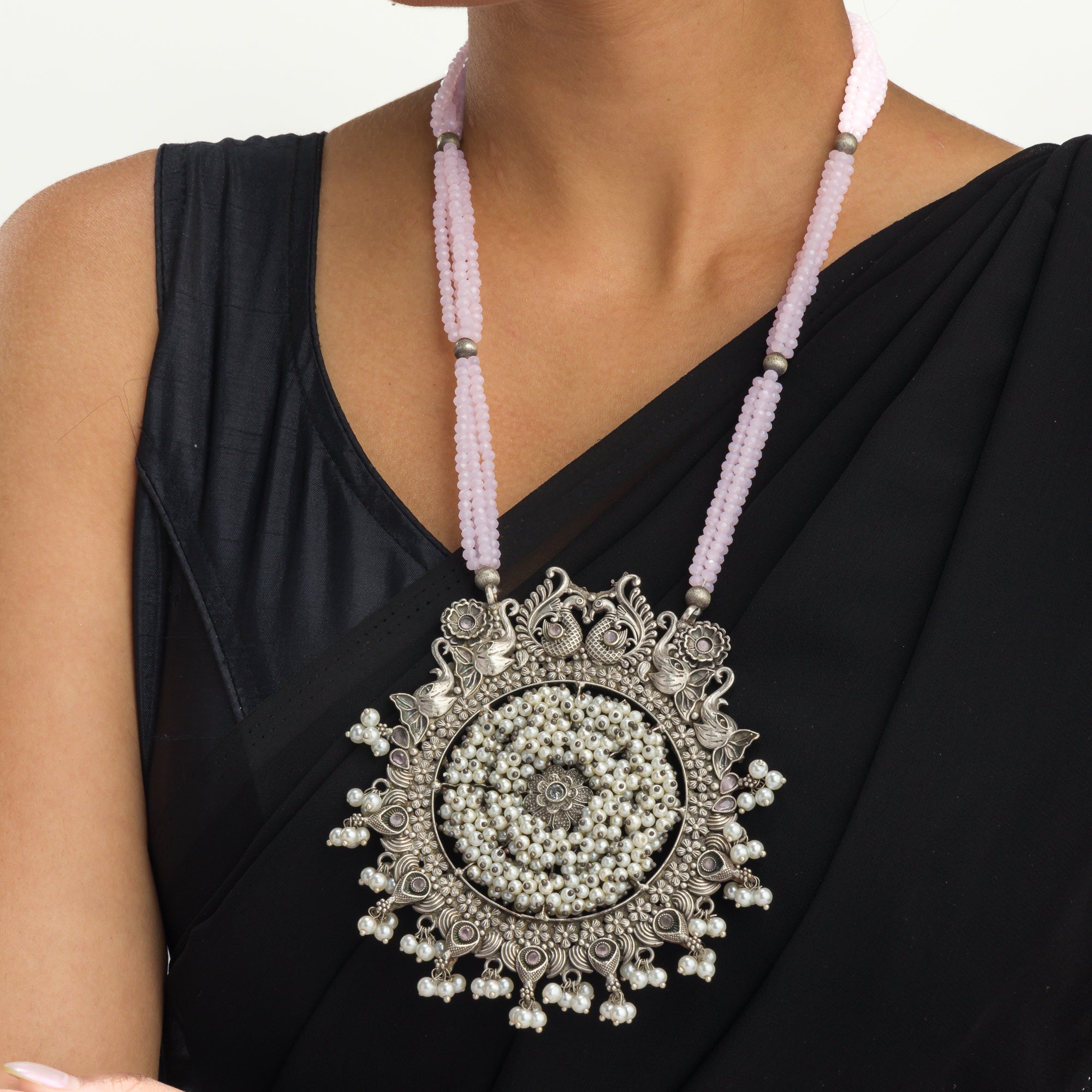 "Long oxidized necklace with pink and white pearls adds vintage elegance."