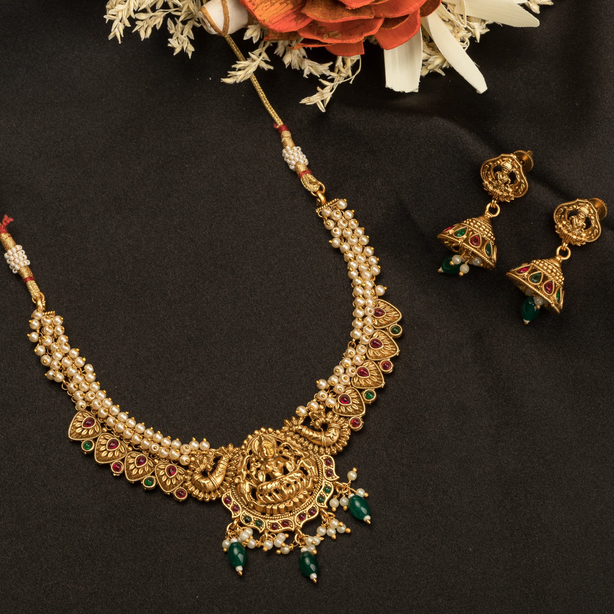 "Gold-tone necklace with white pearl and green Kundan for a timeless traditional look."