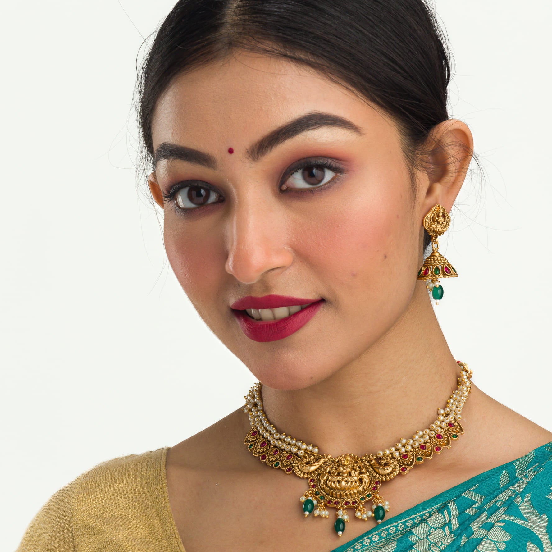 "Gold-tone necklace with white pearl and green Kundan for a timeless traditional look."