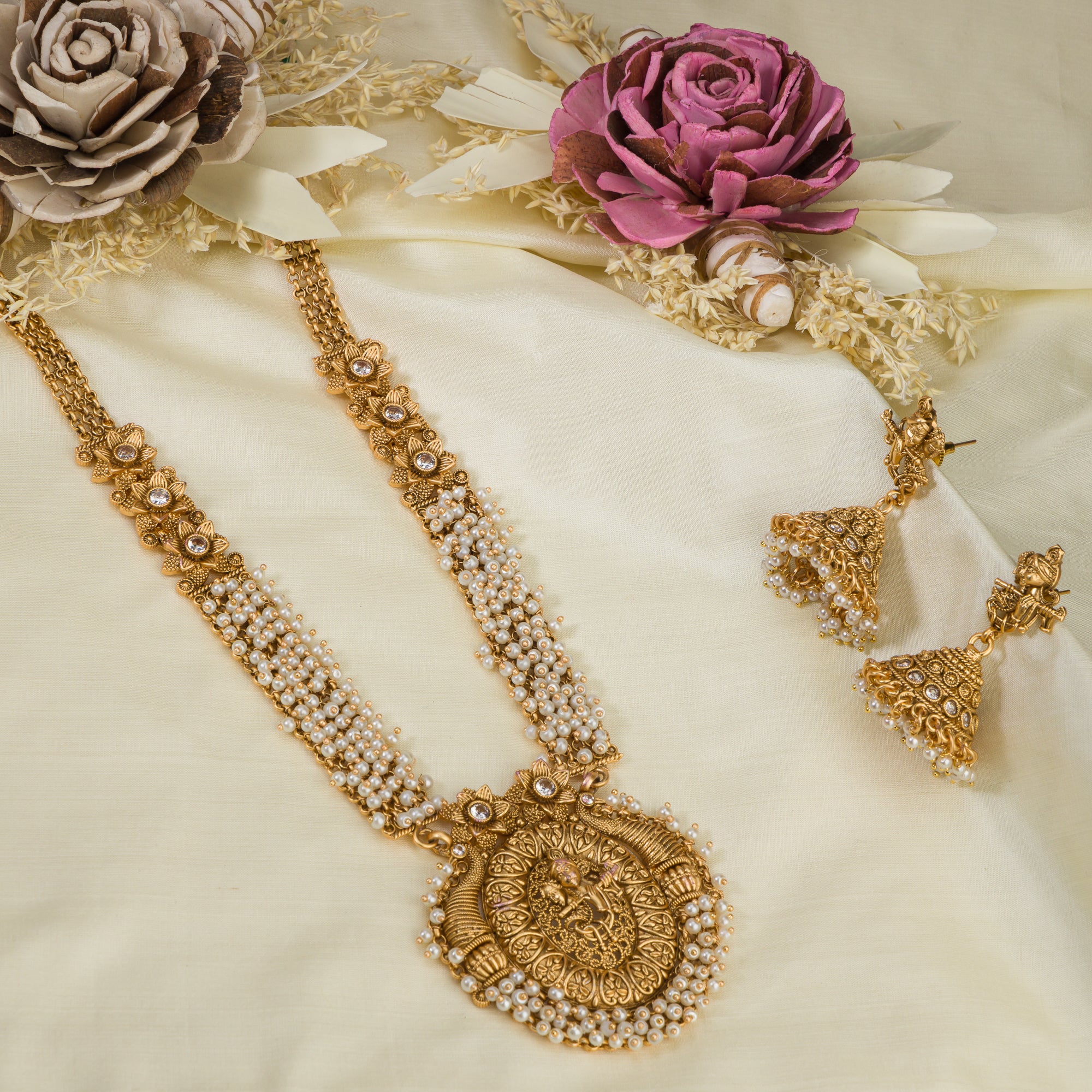Golden Radha Krishna long necklace set with pearls and matching jhumkas for a divine festive look.