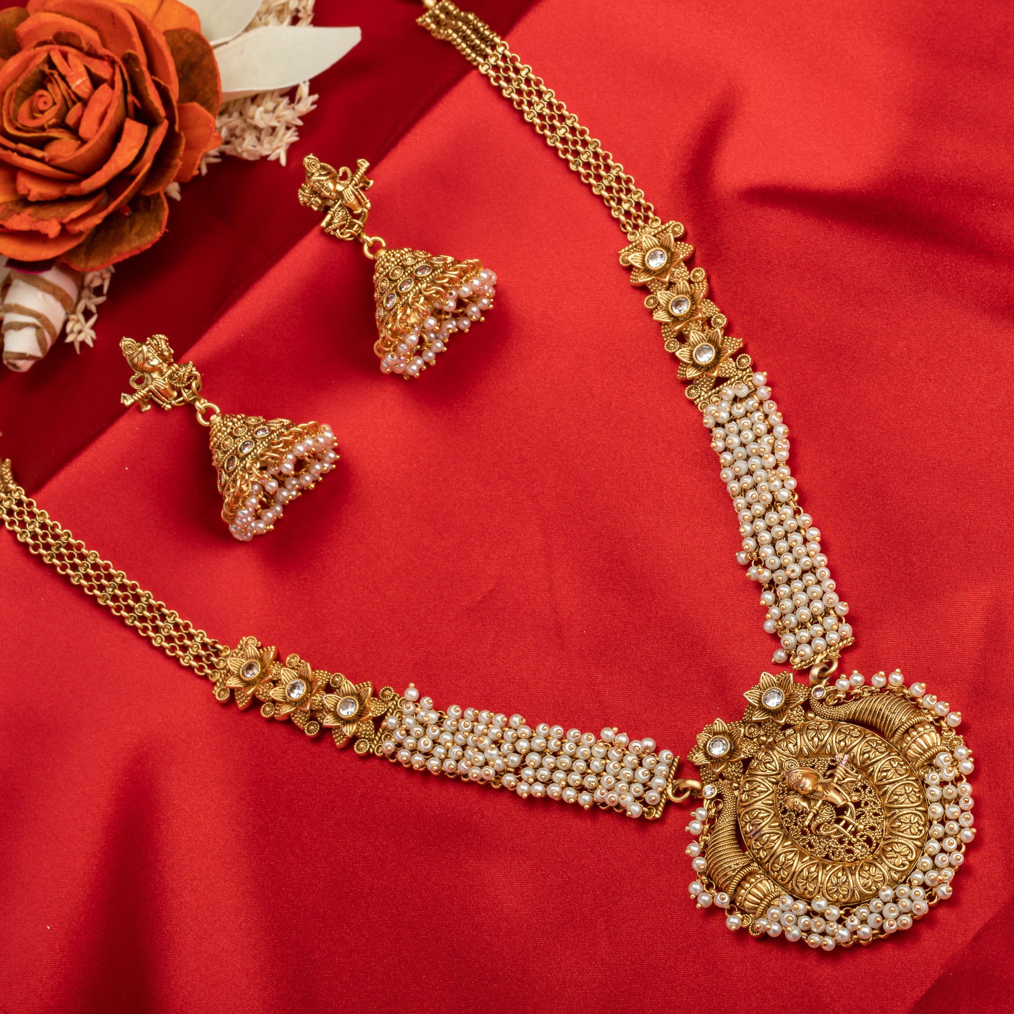 Golden Radha Krishna long necklace set with pearls and matching jhumkas for a divine festive look.