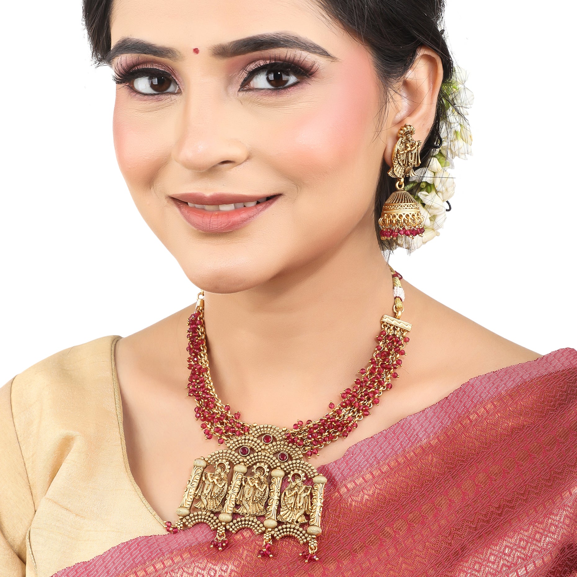Radha Krishna temple necklace set with red pearls, showcasing intricate gold-tone craftsmanship.