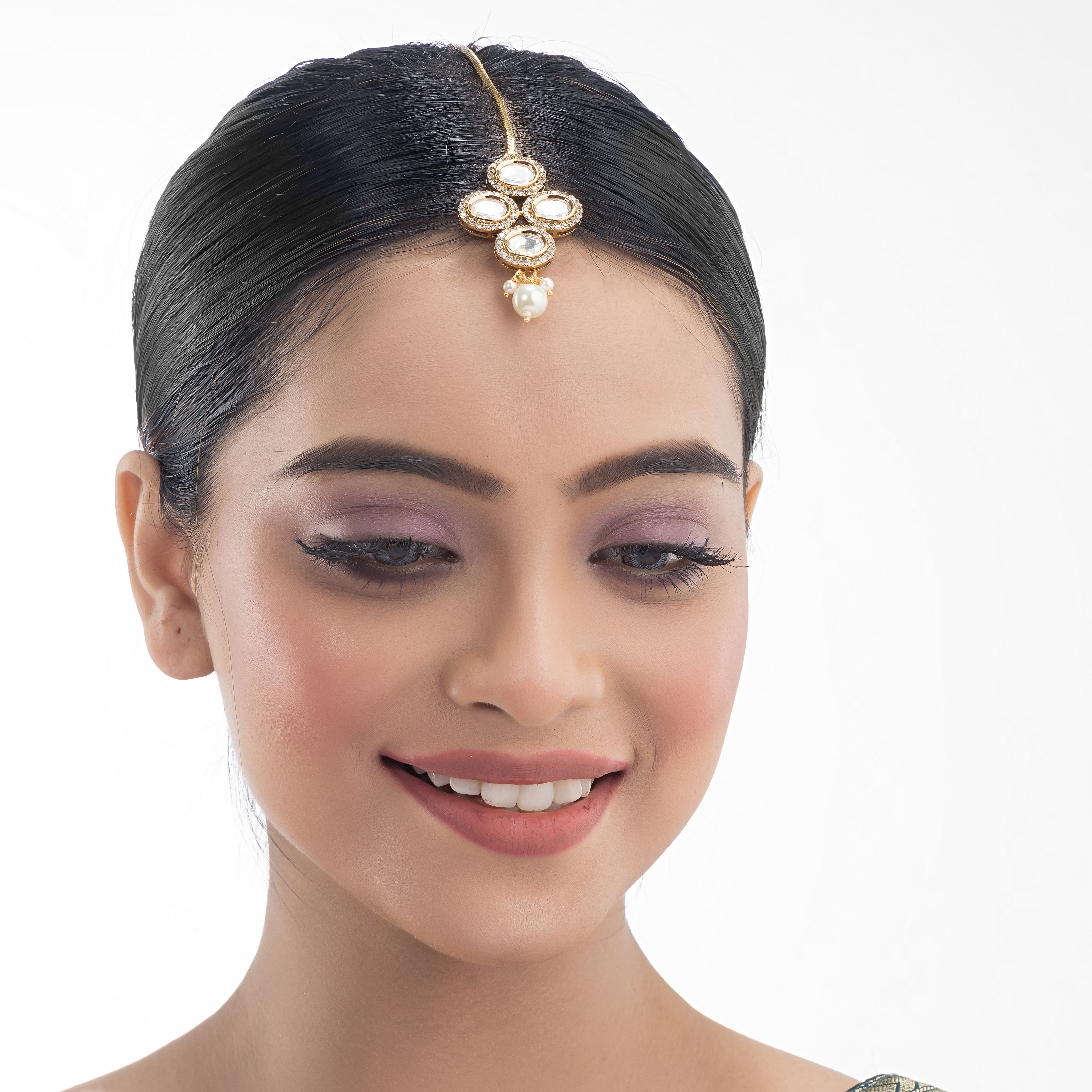 Kundan-studded goldtone maang tika with intricate detailing for a festive touch.