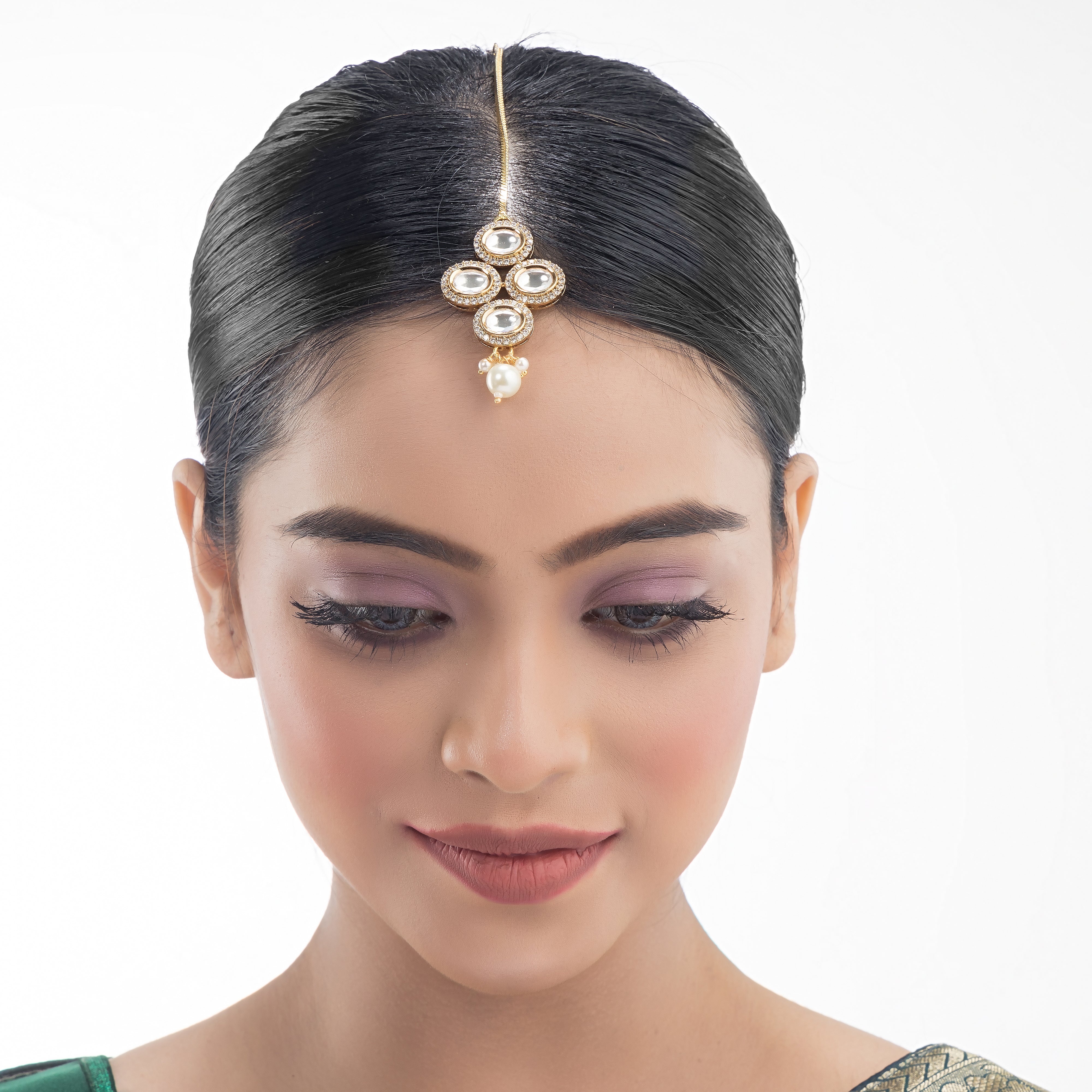 Kundan-studded goldtone maang tika with intricate detailing for a festive touch.