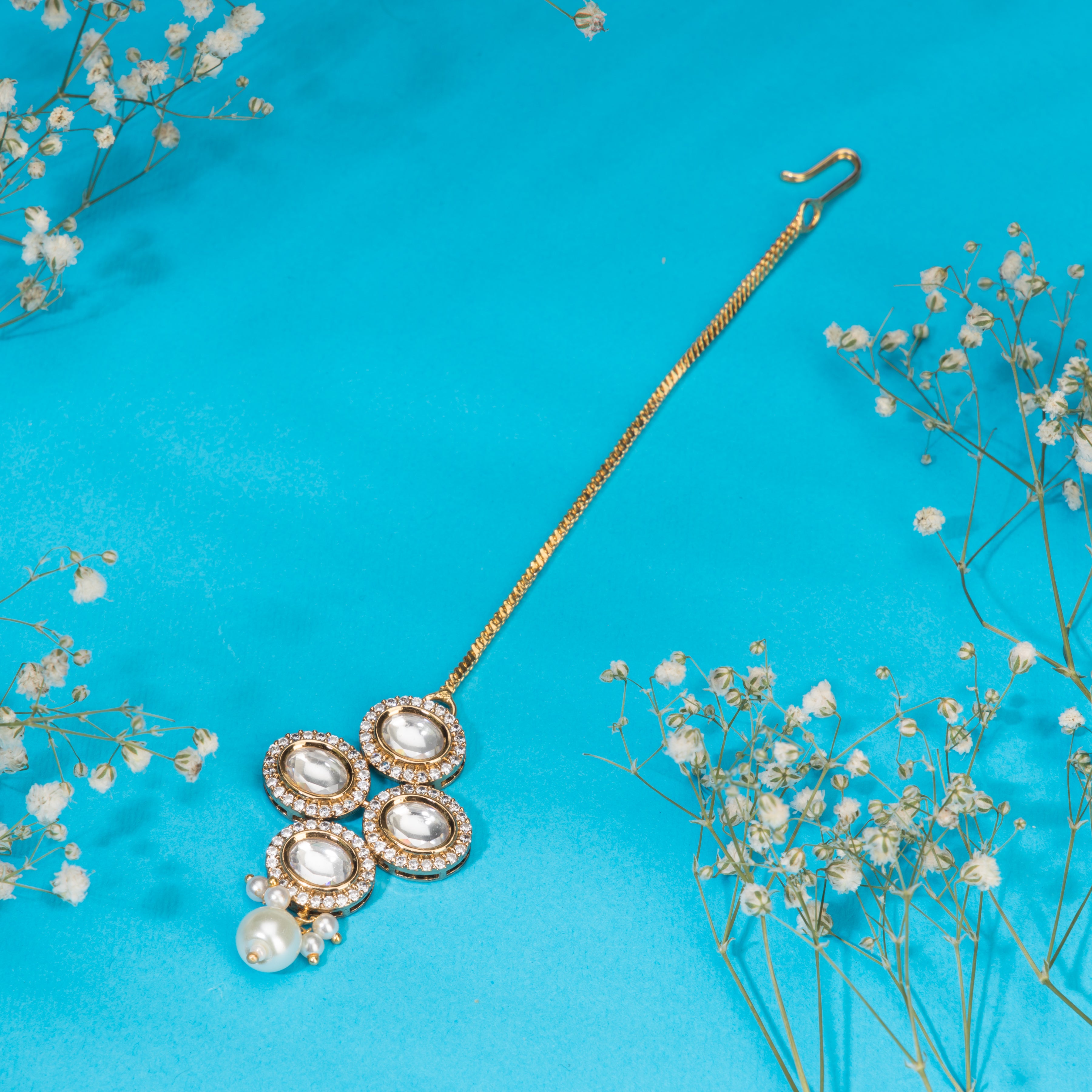 Kundan-studded goldtone maang tika with intricate detailing for a festive touch.