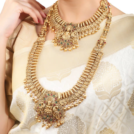 "Goldtone Laxmi Maa crafted long necklace set with matching earrings and Maang Tikka for festive elegance."