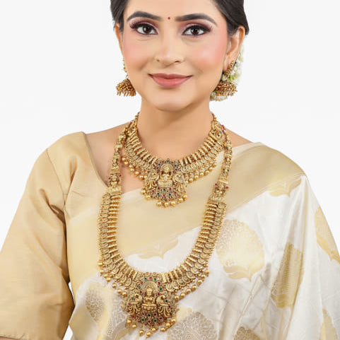 "Goldtone Laxmi Maa crafted long necklace set with matching earrings and Maang Tikka for festive elegance."