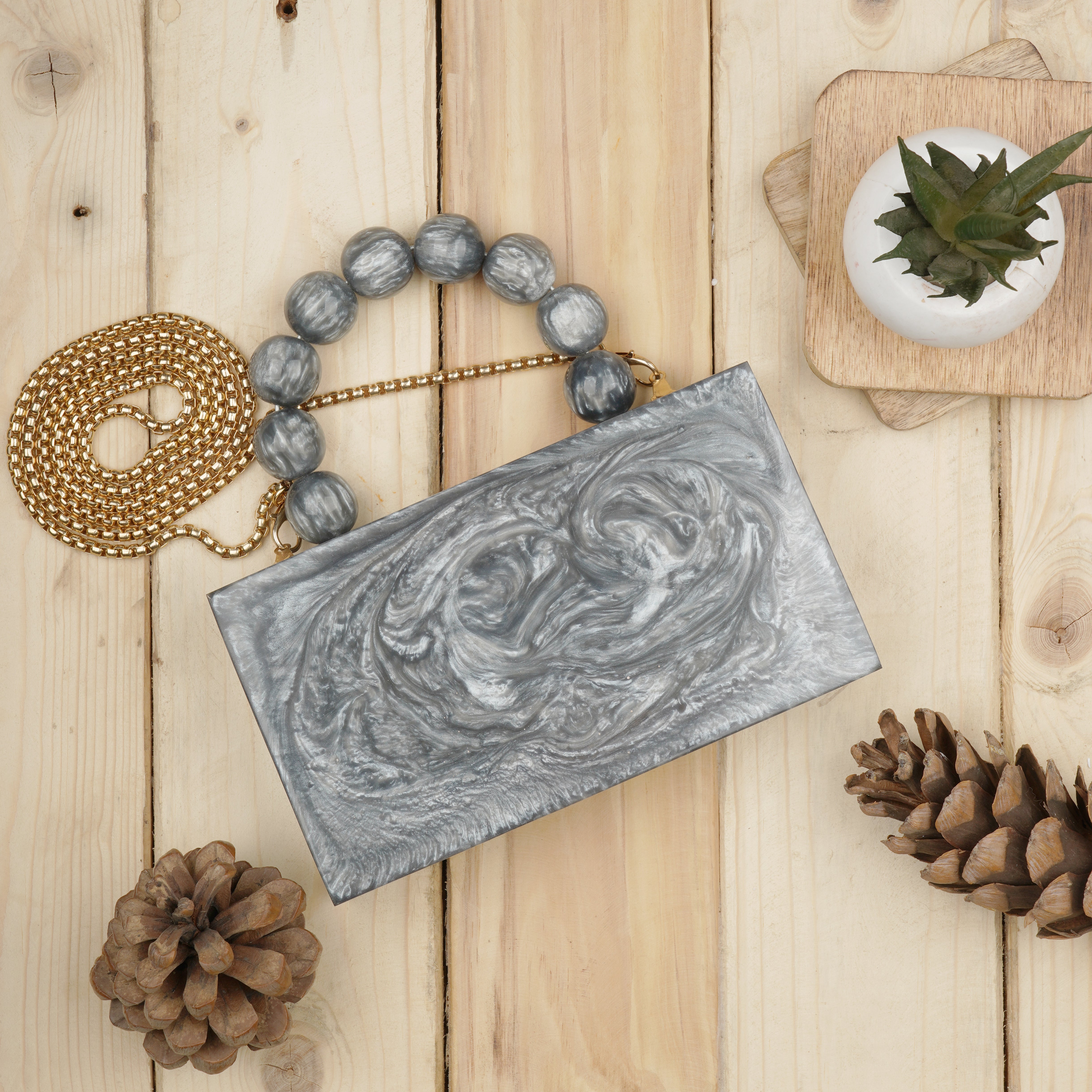Grey resin clutch with velvet lining, heavy-duty sling, and extra pocket for convenient storage.