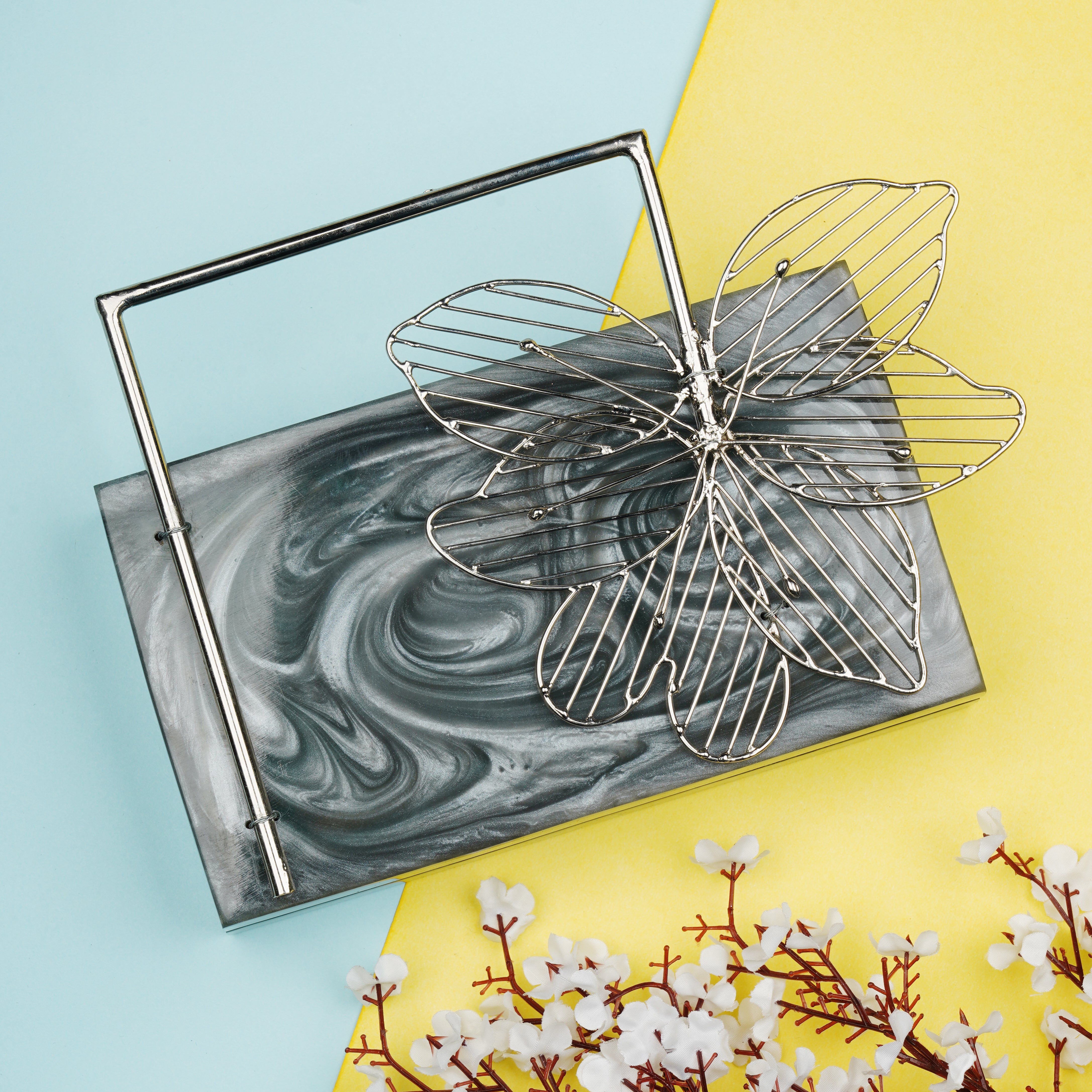 Exclusive grey resin clutch with flower handles, heavy sling, and extra pocket for practicality.