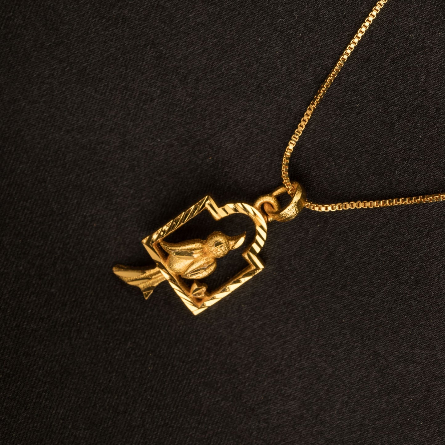 A GOLD-TONE PENDANT FEATURING A BIRD IN A NEST COMBINES CHARMING DETAILS WITH A WARM, ELEGANT FINISH.