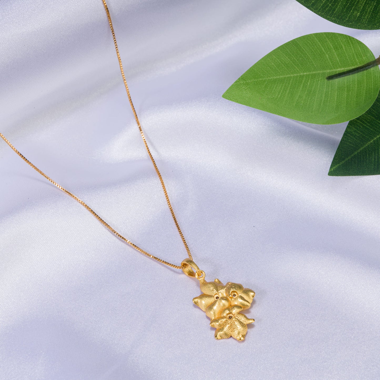 GOLD-TONE PENDANT FEATURING THREE FLOWERS.