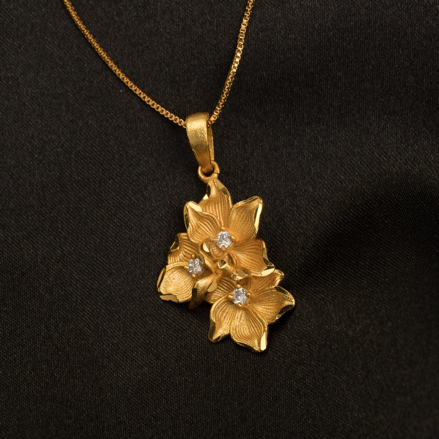 GOLD-TONE PENDANT FEATURING THREE FLOWERS.