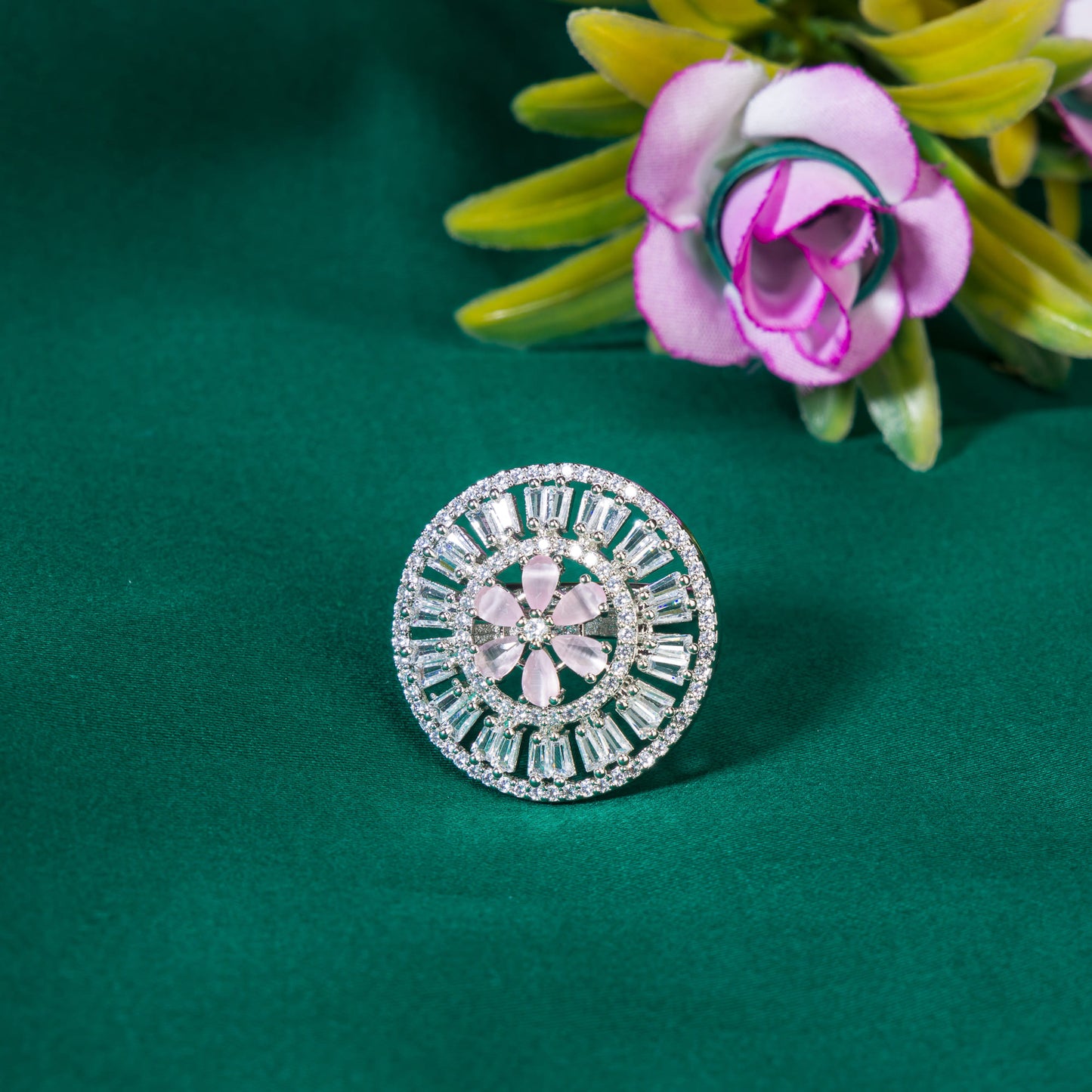 A ZIRCON FINGER RING WITH A PINK FLOWER IN THE MIDDLE COMBINES SPARKLING ELEGANCE WITH A CHARMING, VIBRANT FOCAL POINT.