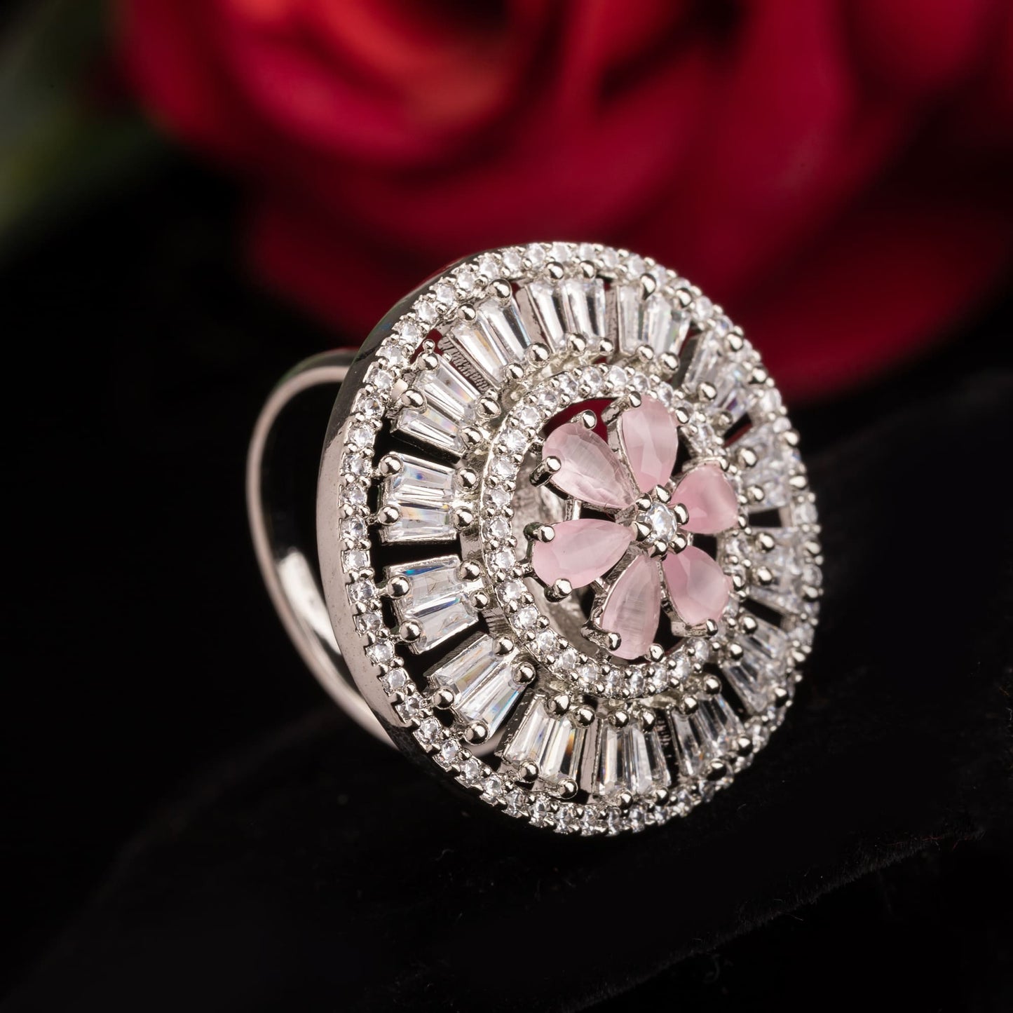 A ZIRCON FINGER RING WITH A PINK FLOWER IN THE MIDDLE COMBINES SPARKLING ELEGANCE WITH A CHARMING, VIBRANT FOCAL POINT.