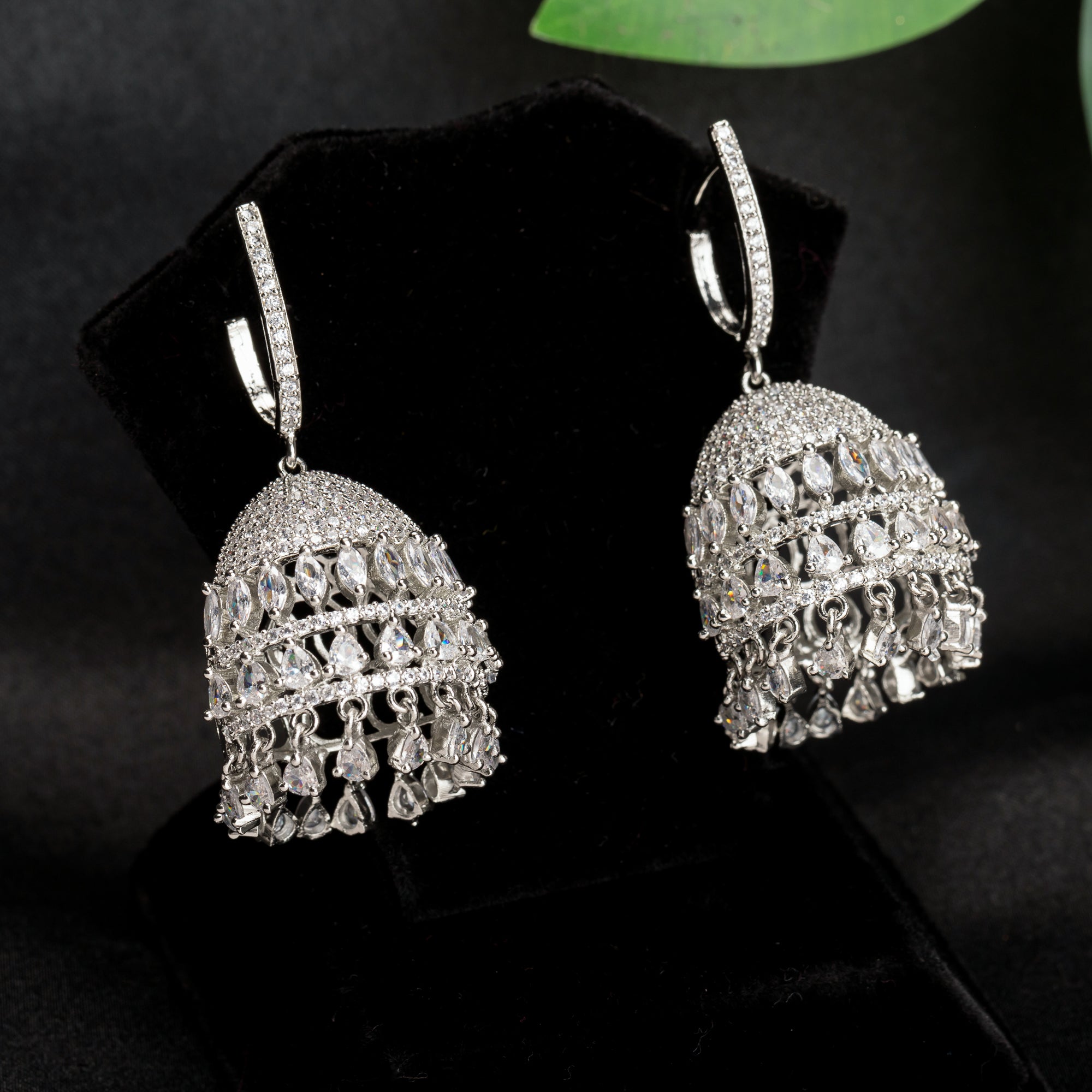 "Zircon jhumka earrings in silver combine intricate detailing with radiant sparkle for a stunning, traditional party wear touch."
