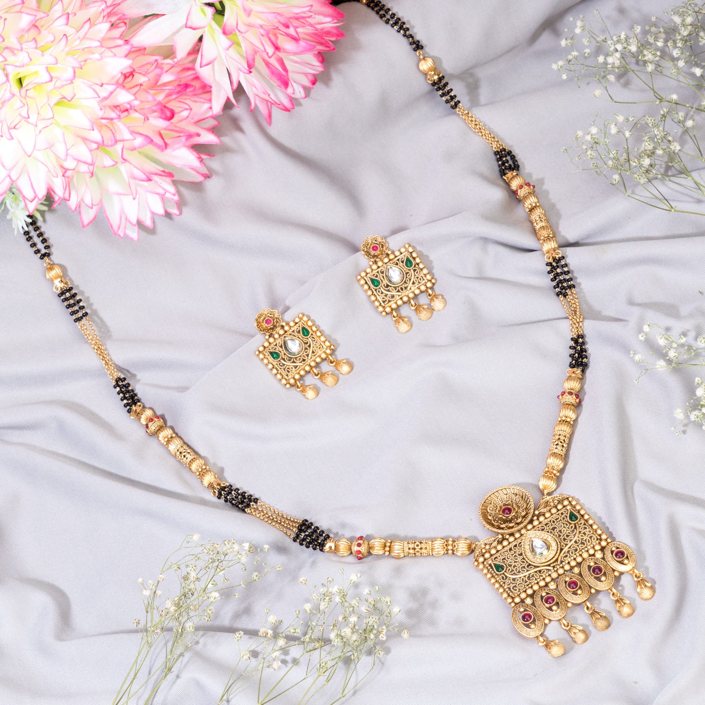 LONG GOLD-TONE MANGALSUTRA WITH BLACK BEADS AND STONES STUDDED.