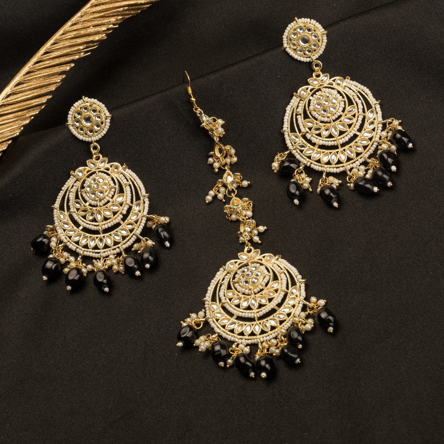 "BLACK KUNDAN SET IN GOLD POLISH, PAIRED WITH A MATCHING MAANGTIKA, EXUDES REGAL SOPHISTICATION AND TIMELESS ELEGANCE."