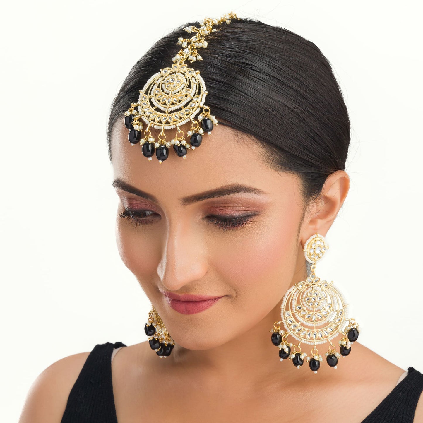 "BLACK KUNDAN SET IN GOLD POLISH, PAIRED WITH A MATCHING MAANGTIKA, EXUDES REGAL SOPHISTICATION AND TIMELESS ELEGANCE."