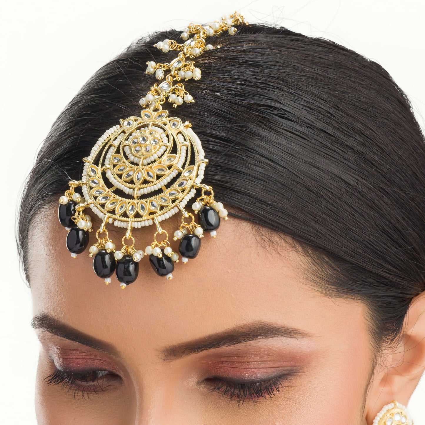 "BLACK KUNDAN SET IN GOLD POLISH, PAIRED WITH A MATCHING MAANGTIKA, EXUDES REGAL SOPHISTICATION AND TIMELESS ELEGANCE."