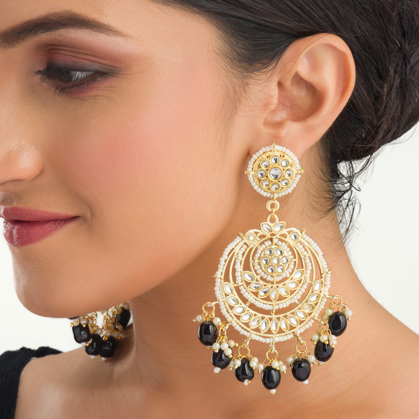 "BLACK KUNDAN SET IN GOLD POLISH, PAIRED WITH A MATCHING MAANGTIKA, EXUDES REGAL SOPHISTICATION AND TIMELESS ELEGANCE."