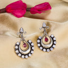 "Oxidized studs with red and white stones create a striking vintage-inspired contrast."
