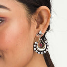 "Oxidized studs with red and white stones create a striking vintage-inspired contrast."
