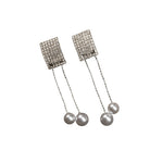 "Silver zircon earrings with hanging pearls offer elegant sparkle and sophistication."
