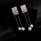 "Silver zircon earrings with hanging pearls offer elegant sparkle and sophistication."
