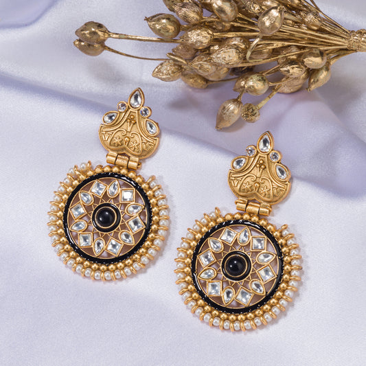 GOLD-TONE EARRINGS WITH A BLACK PEARL IN THE MIDDLE BLEND ELEGANT WARMTH WITH A STRIKING, SOPHISTICATED CONTRAST.